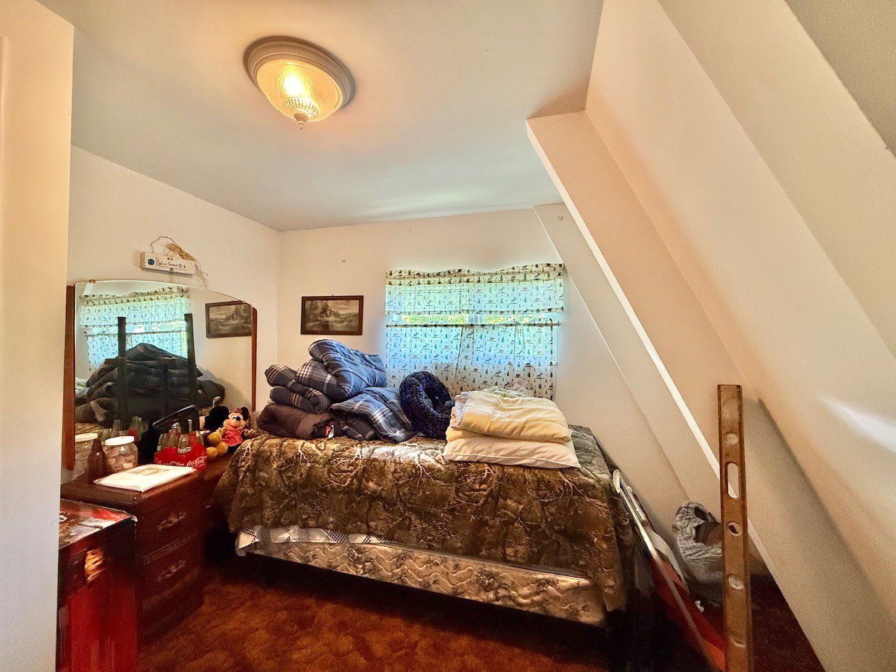 Room featuring a sloped ceiling, two windows with patterned curtains, and a flush-mount ceiling light fixture