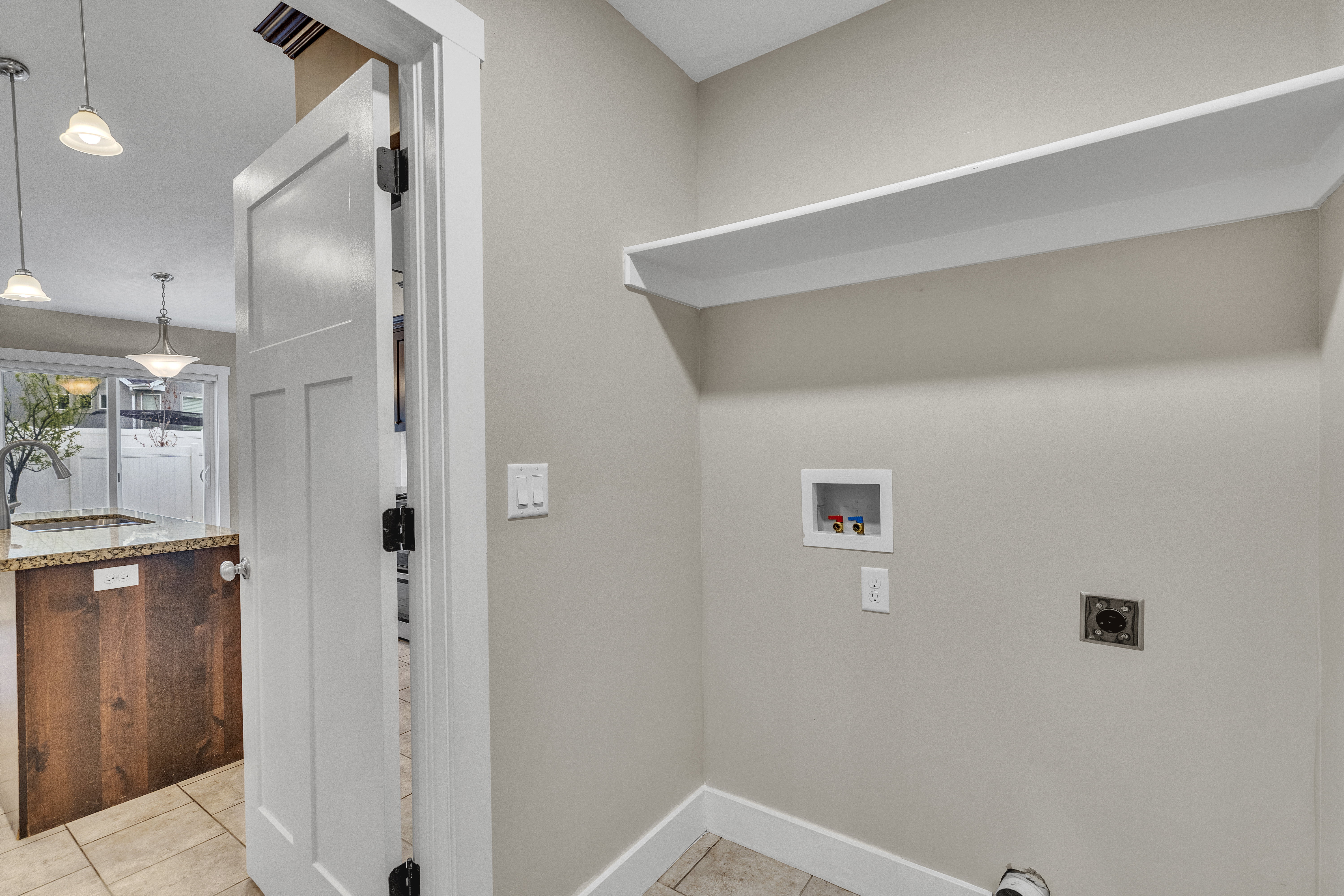 Dedicated utility space featuring a built-in shelf, washer/dryer hookups, and tiled flooring
