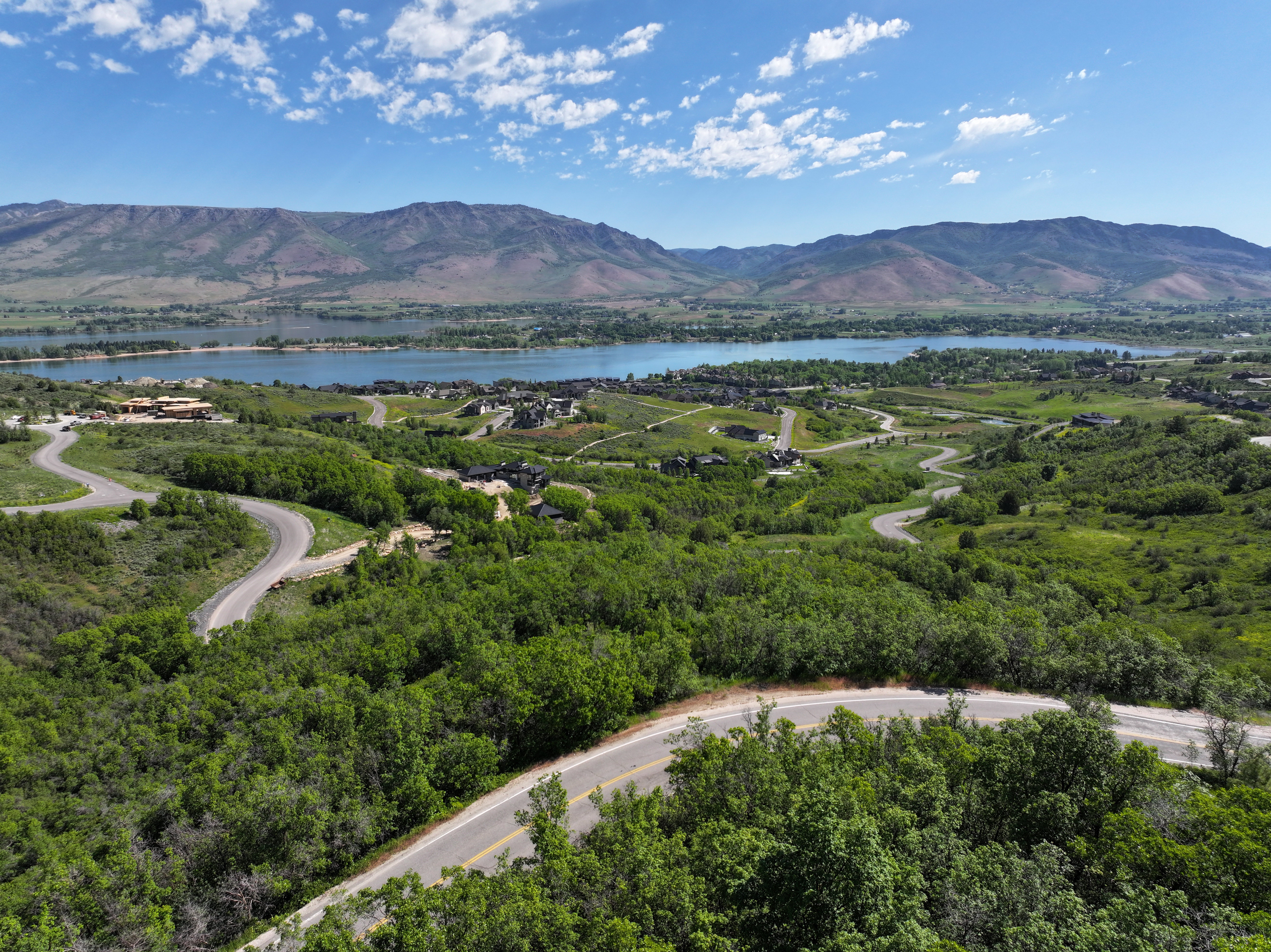 Winding roads traversing a verdant landscape with distant lake and mountain scenery