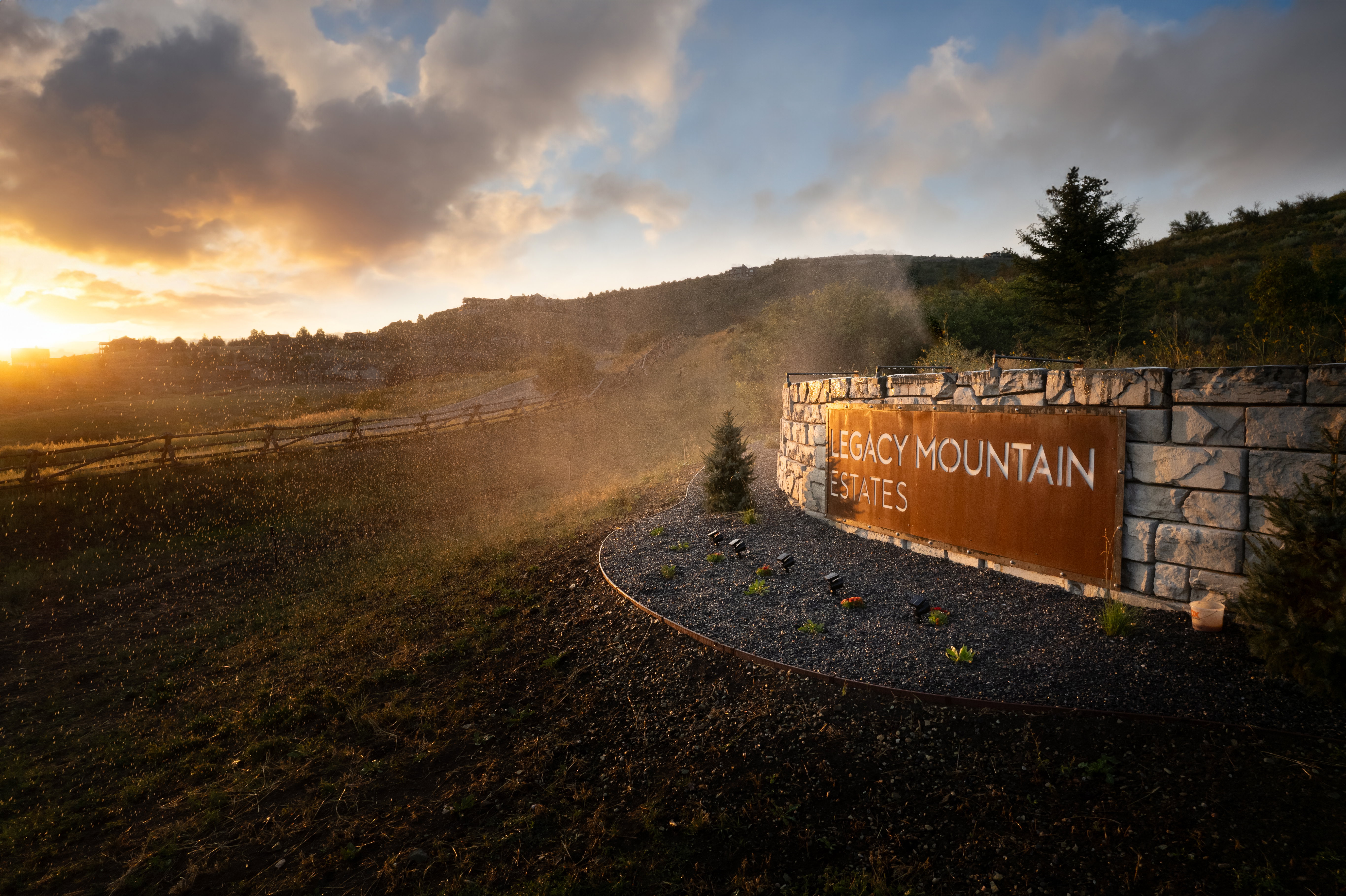 Stone entry monument featuring a large metal sign with "Legacy Mountain Estates" typography