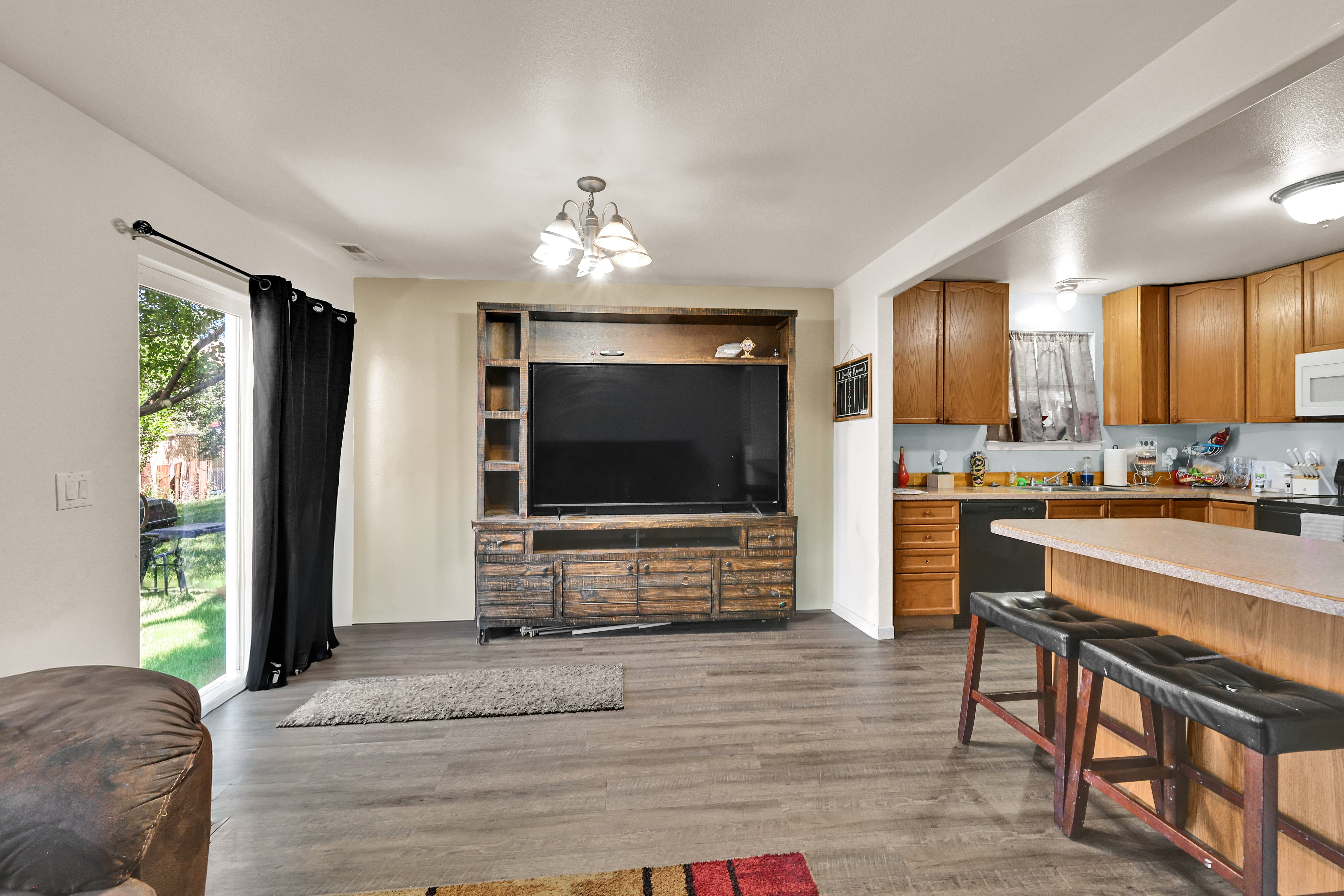 Open-concept living area featuring wood-finish flooring, a built-in media center, and direct access to the exterior through sliding glass doors