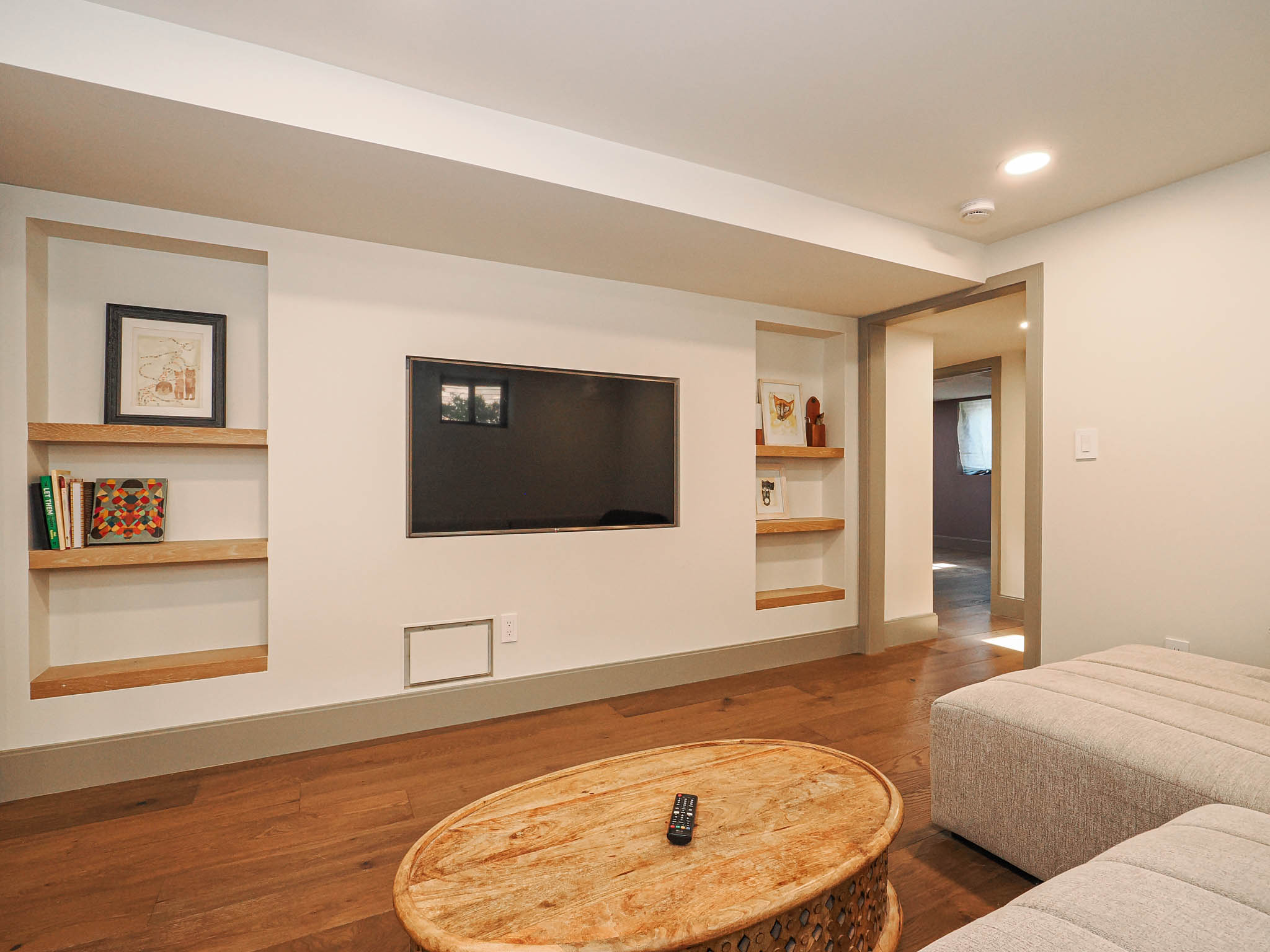 Recessed entertainment wall featuring a mounted display, built-in shelving, and wood-finish flooring