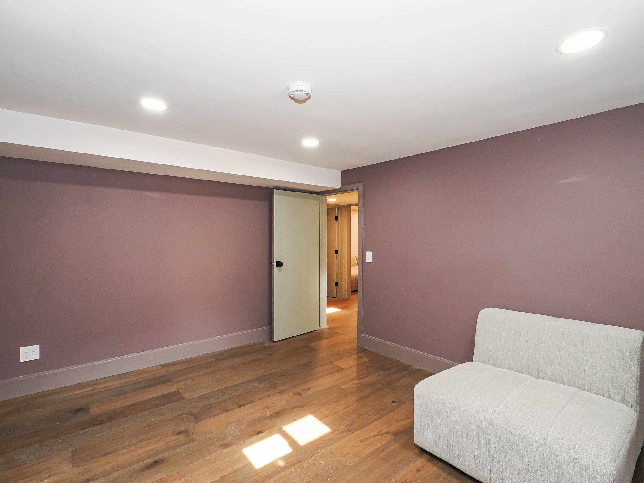 Spacious room with wood-finish flooring, recessed ceiling lighting, and a neutral-toned door frame