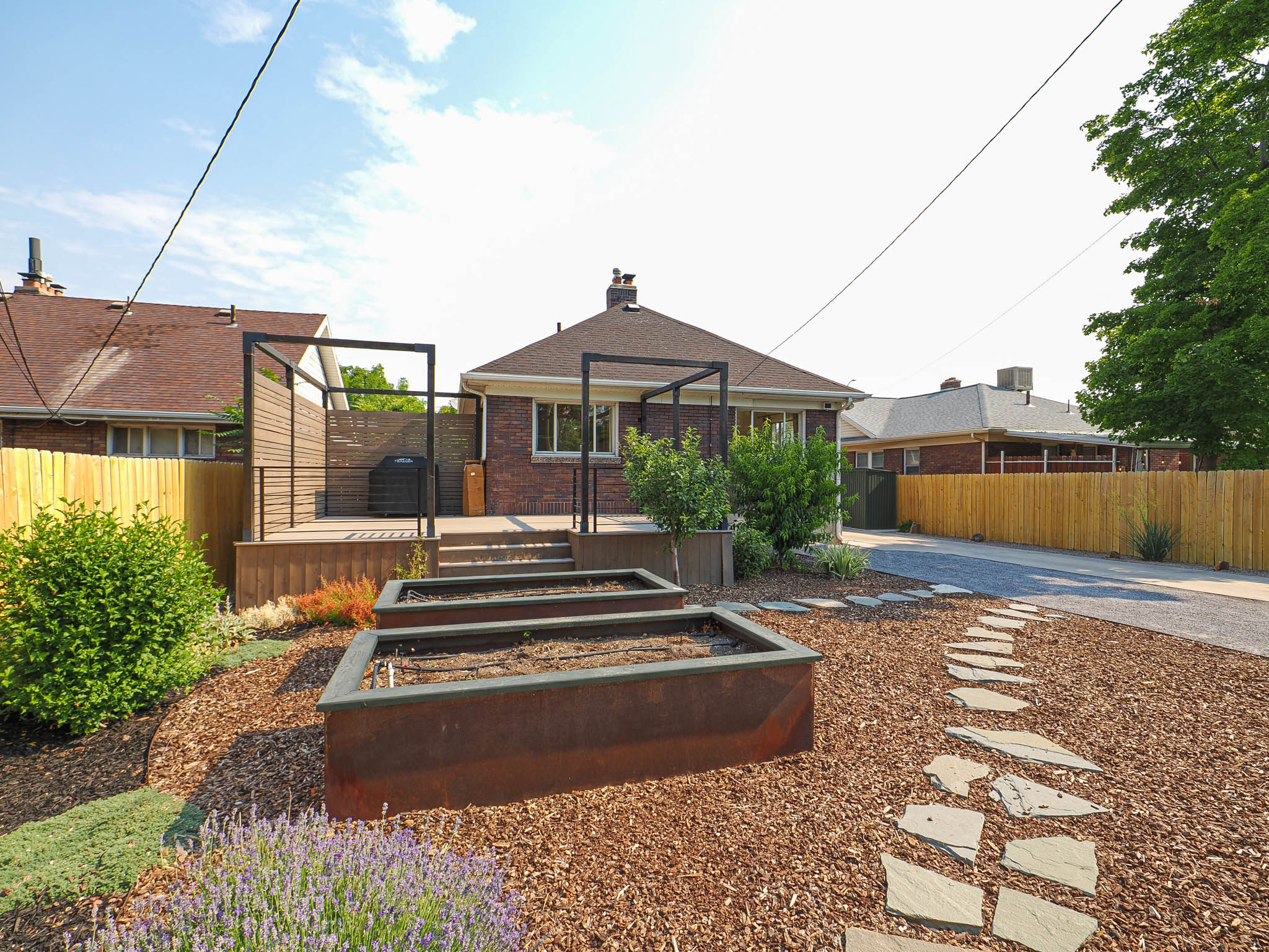 Landscaped backyard featuring multiple raised garden beds, a flagstone path, and a wooden privacy fence