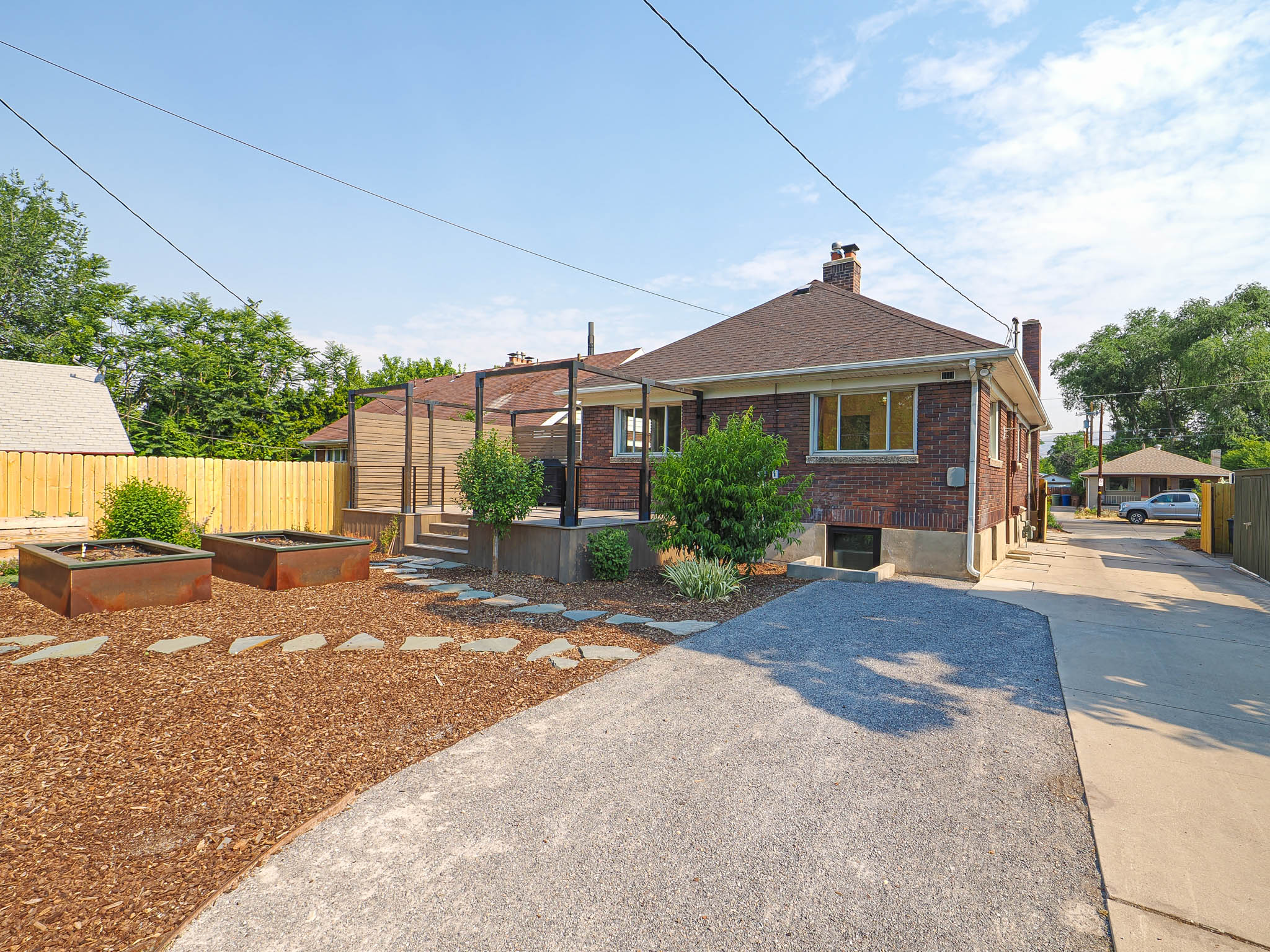 Brick exterior featuring a hip roof, a paved driveway, and a pergola-covered patio