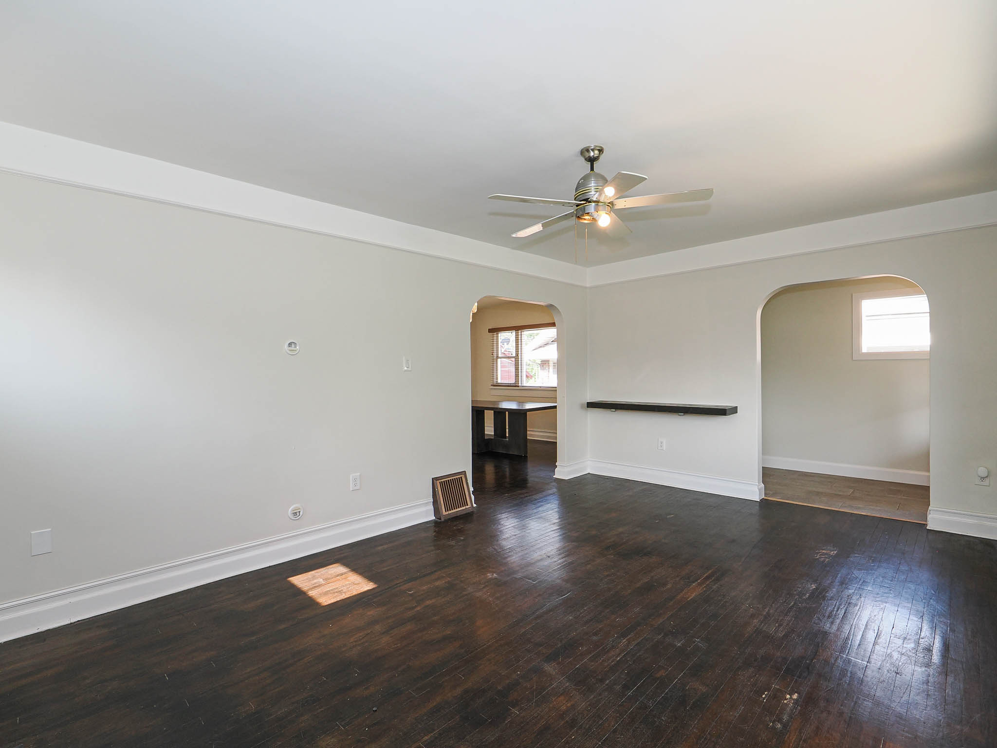 Living area featuring dark wood-finish flooring, light-toned walls, and white crown molding