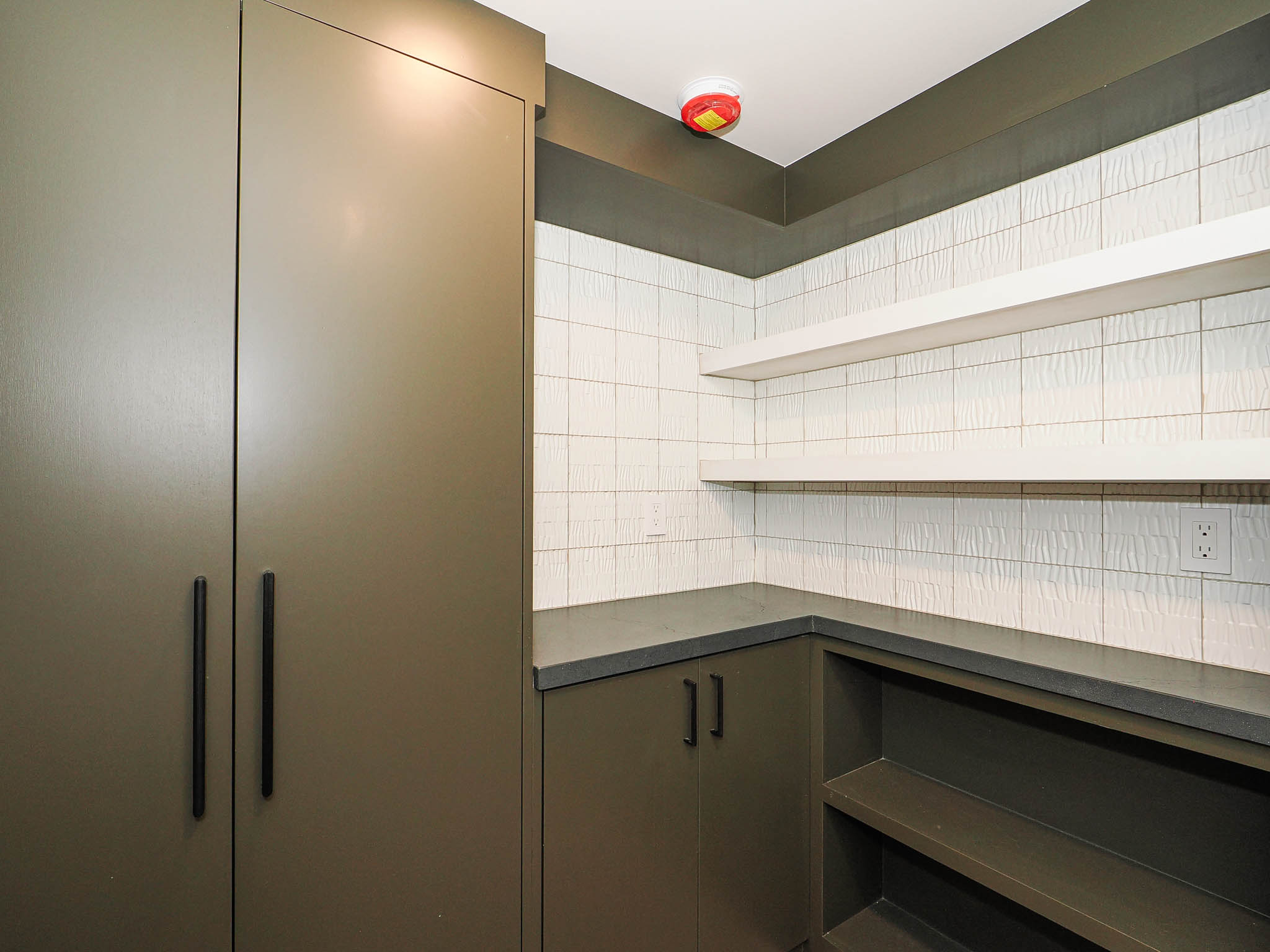 Built-in cabinetry with matte black hardware, integrated shelving, and solid surface countertops