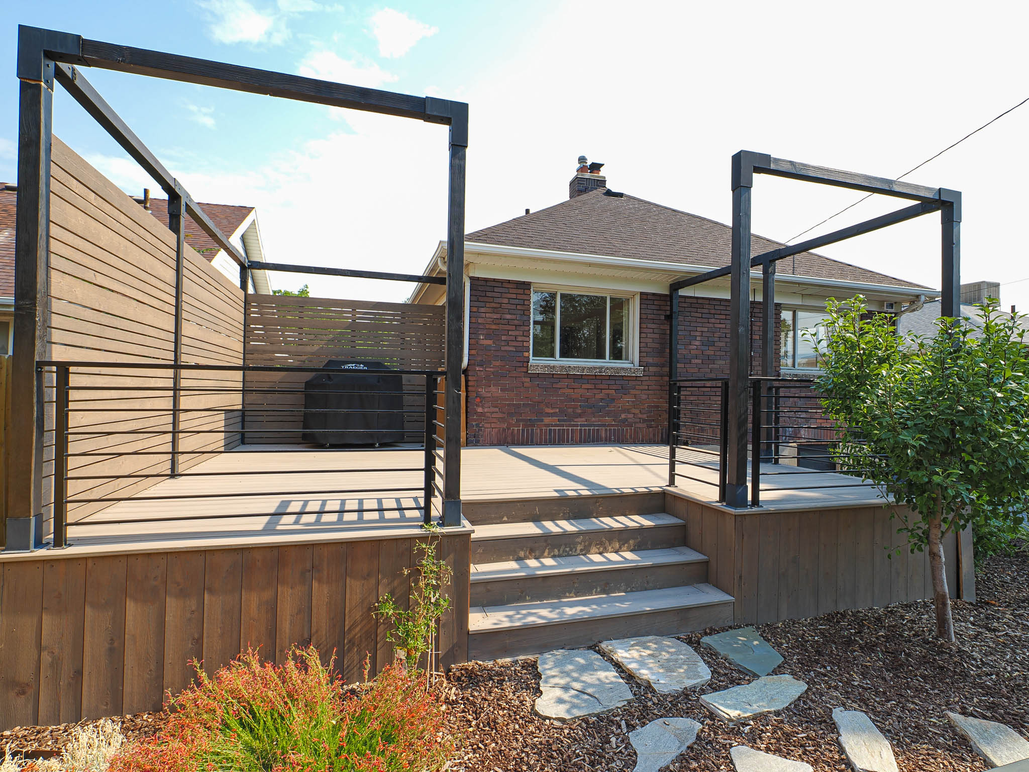 Expansive composite deck featuring a pergola frame and horizontal slat privacy screens