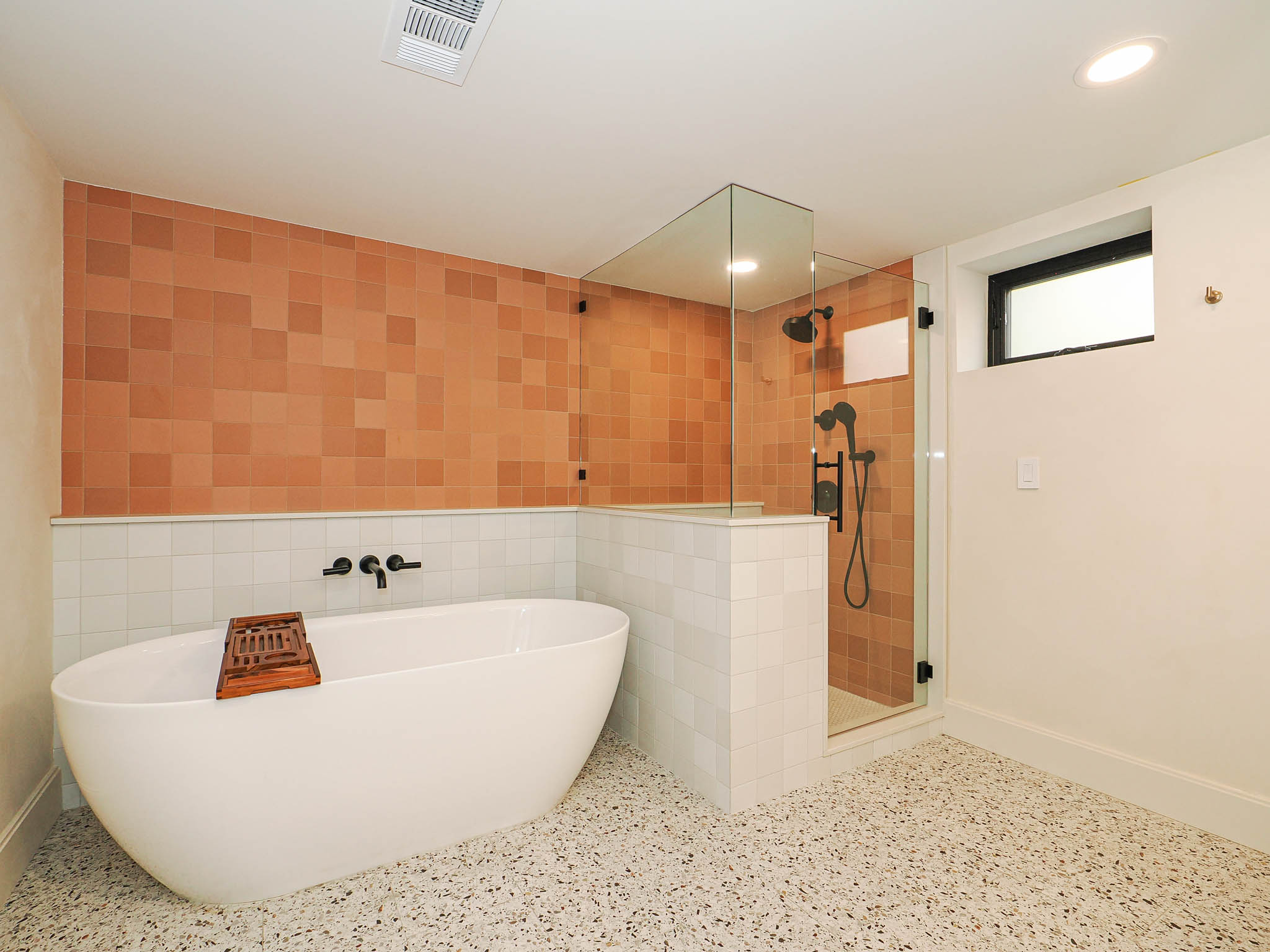 Freestanding soaking tub with wall-mounted matte black fixtures