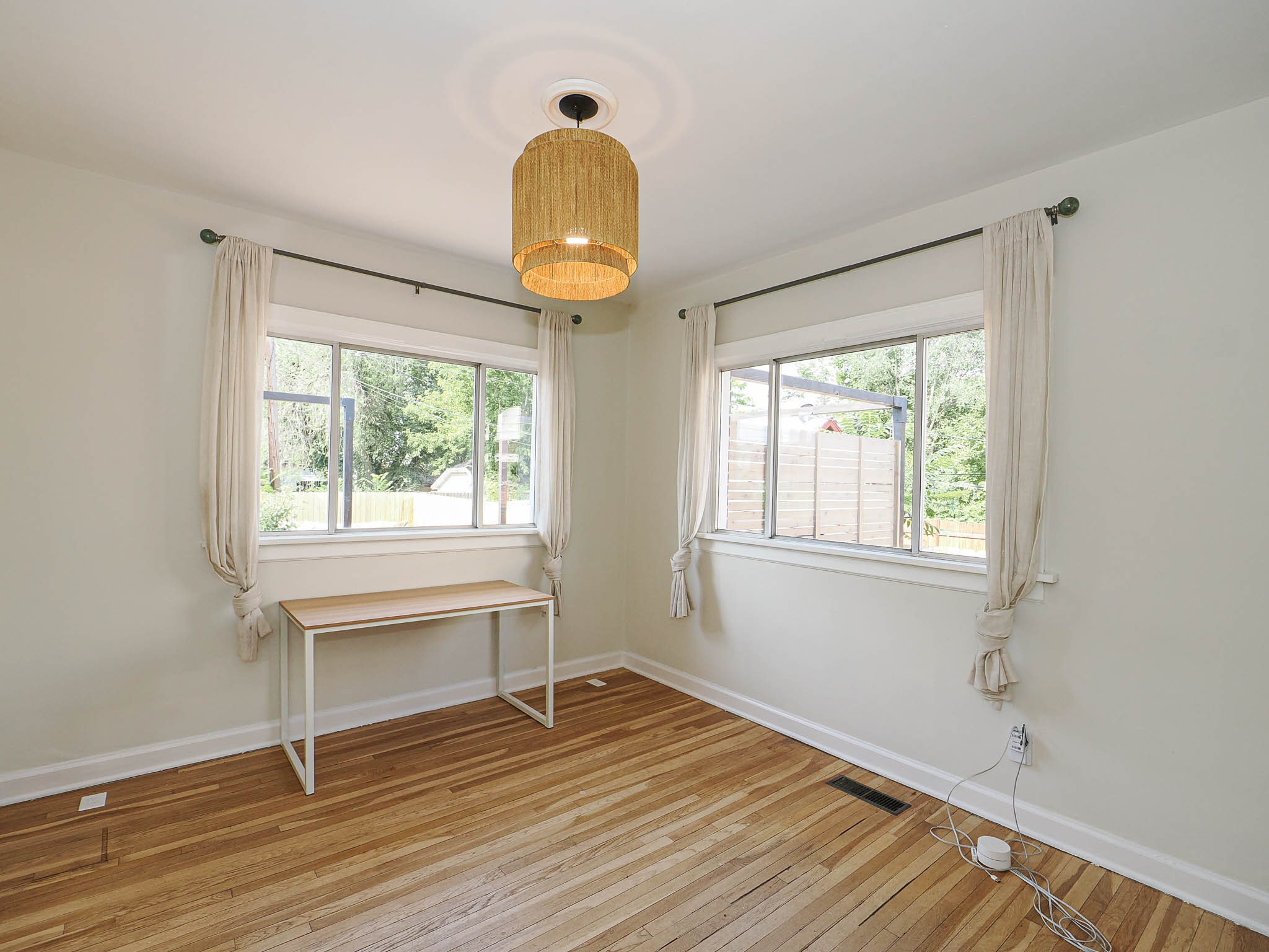 Hardwood flooring with a central ceiling light fixture and two windows