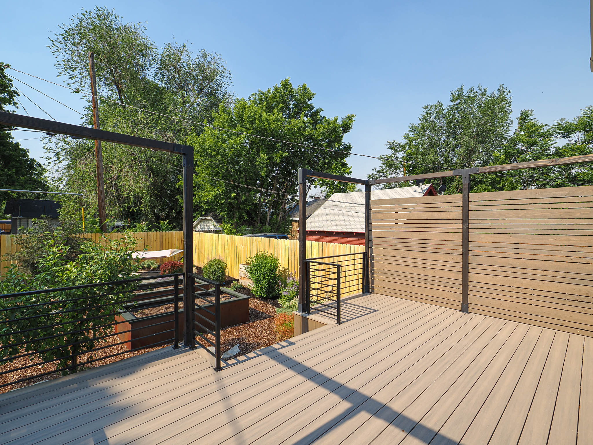 Expansive composite decking featuring perimeter metal railing and a horizontal slatted privacy wall