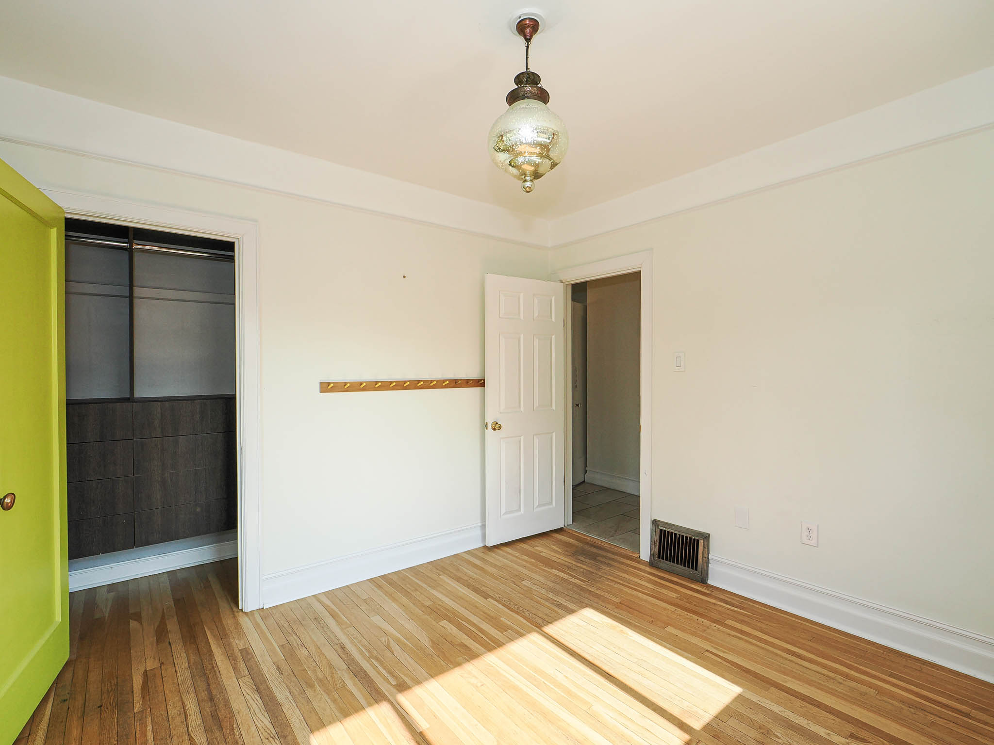 Bright room featuring wood-finish flooring, white trim, and a decorative ceiling light fixture