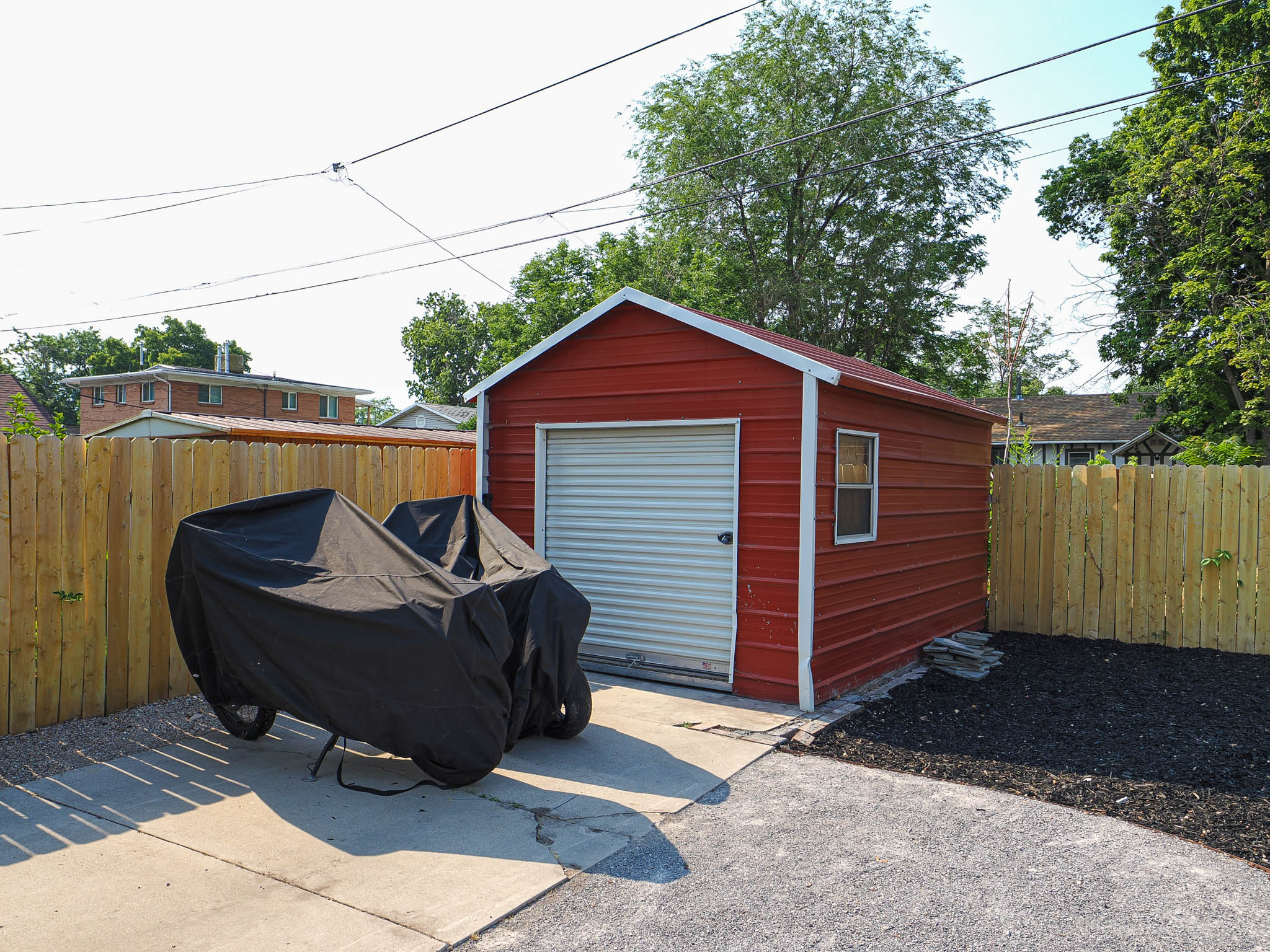 Red storage shed featuring a roll-up door and a single window