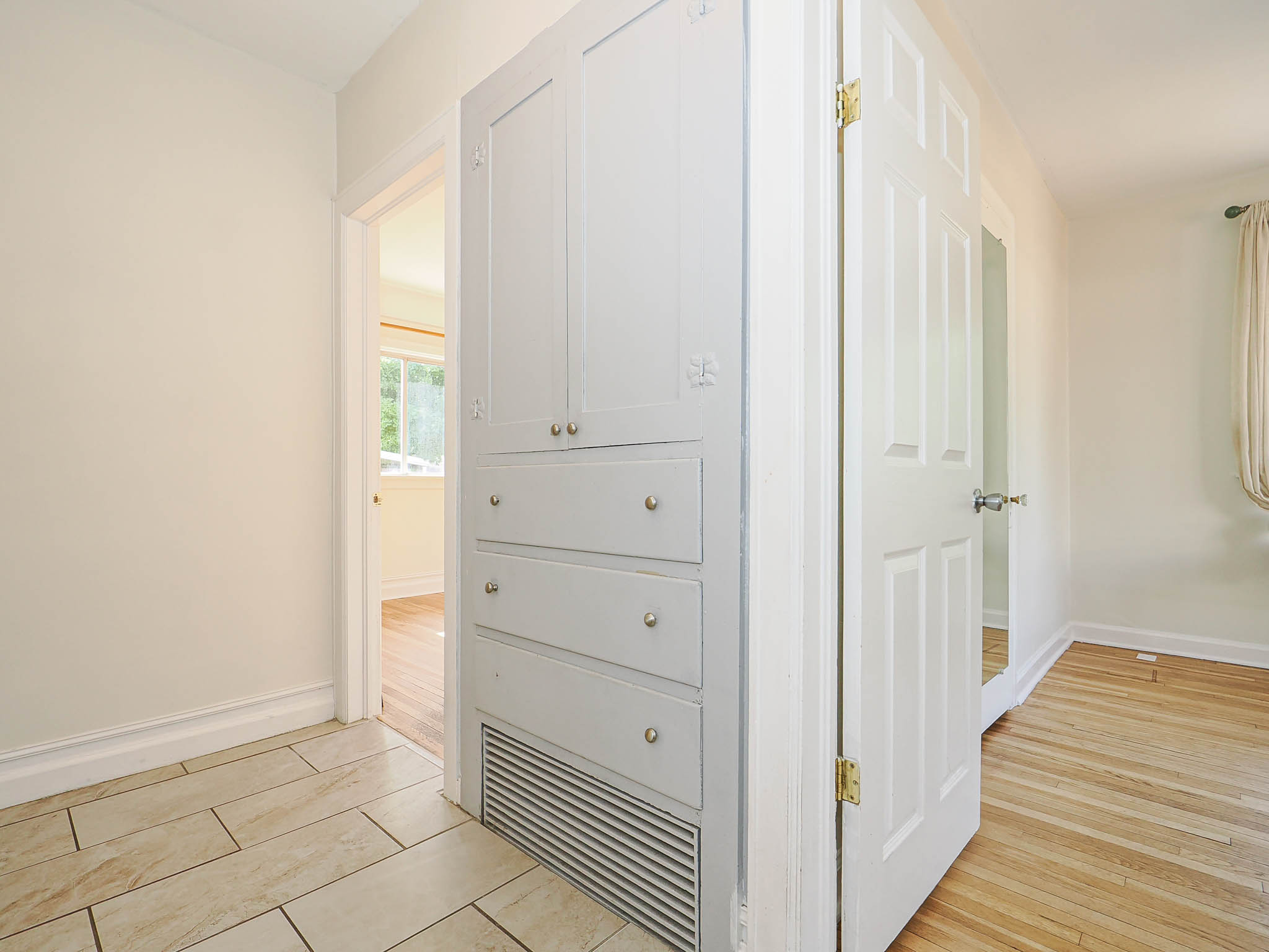 Built-in storage cabinet with recessed panel doors and drawers, featuring gold-toned hardware