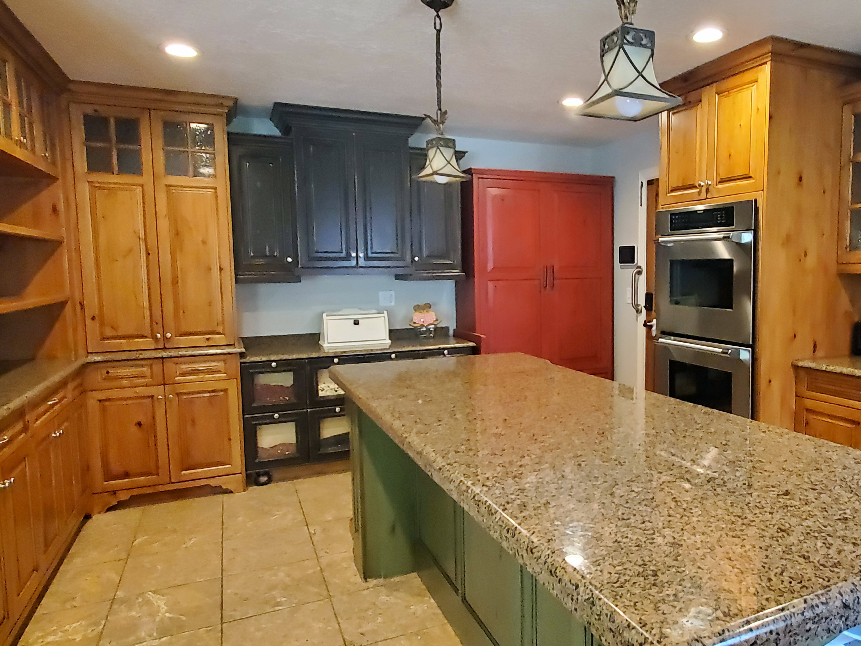 Kitchen featuring a large island with a stone countertop, built-in double ovens, recessed lighting, and tile flooring