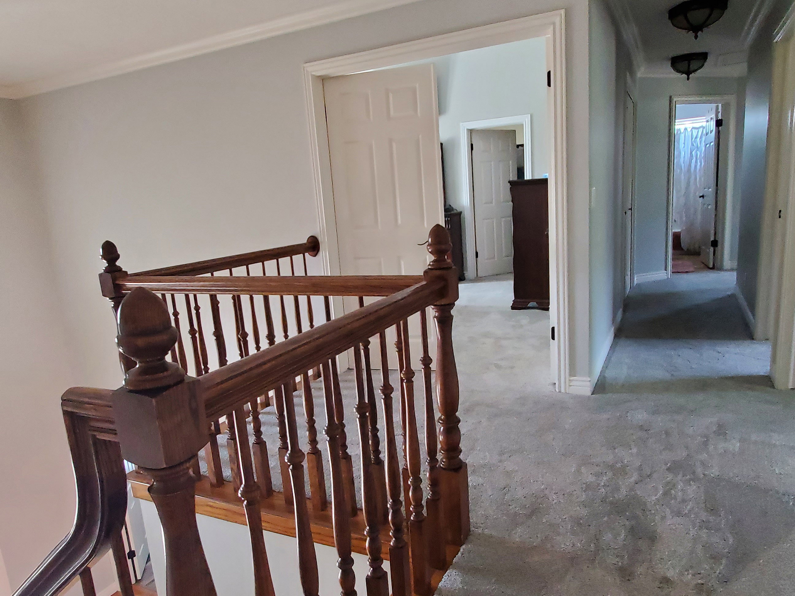 Wood-finish staircase with turned spindles and a carpeted upper landing