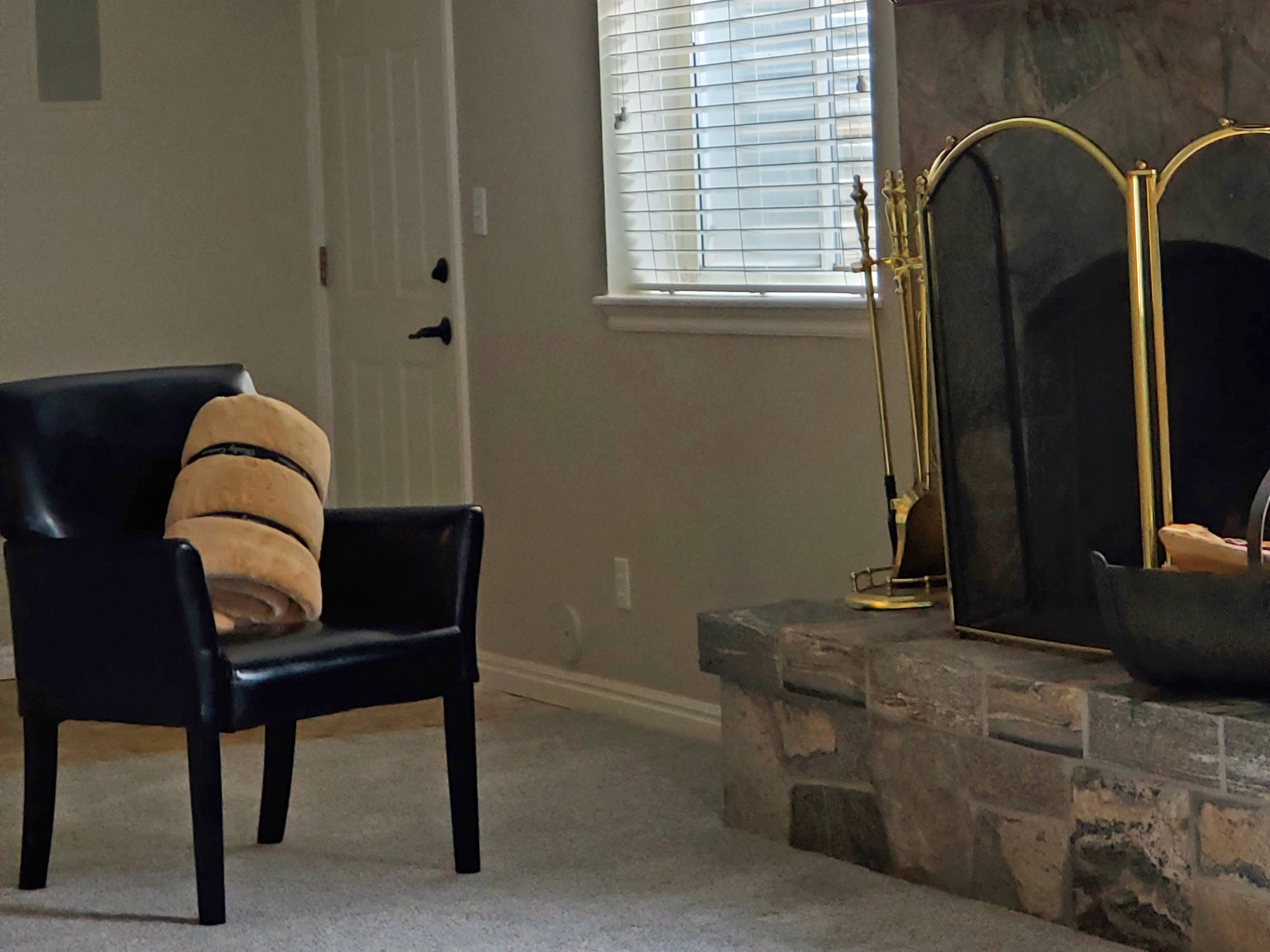 Stone-clad fireplace with a hearth and a window featuring horizontal blinds