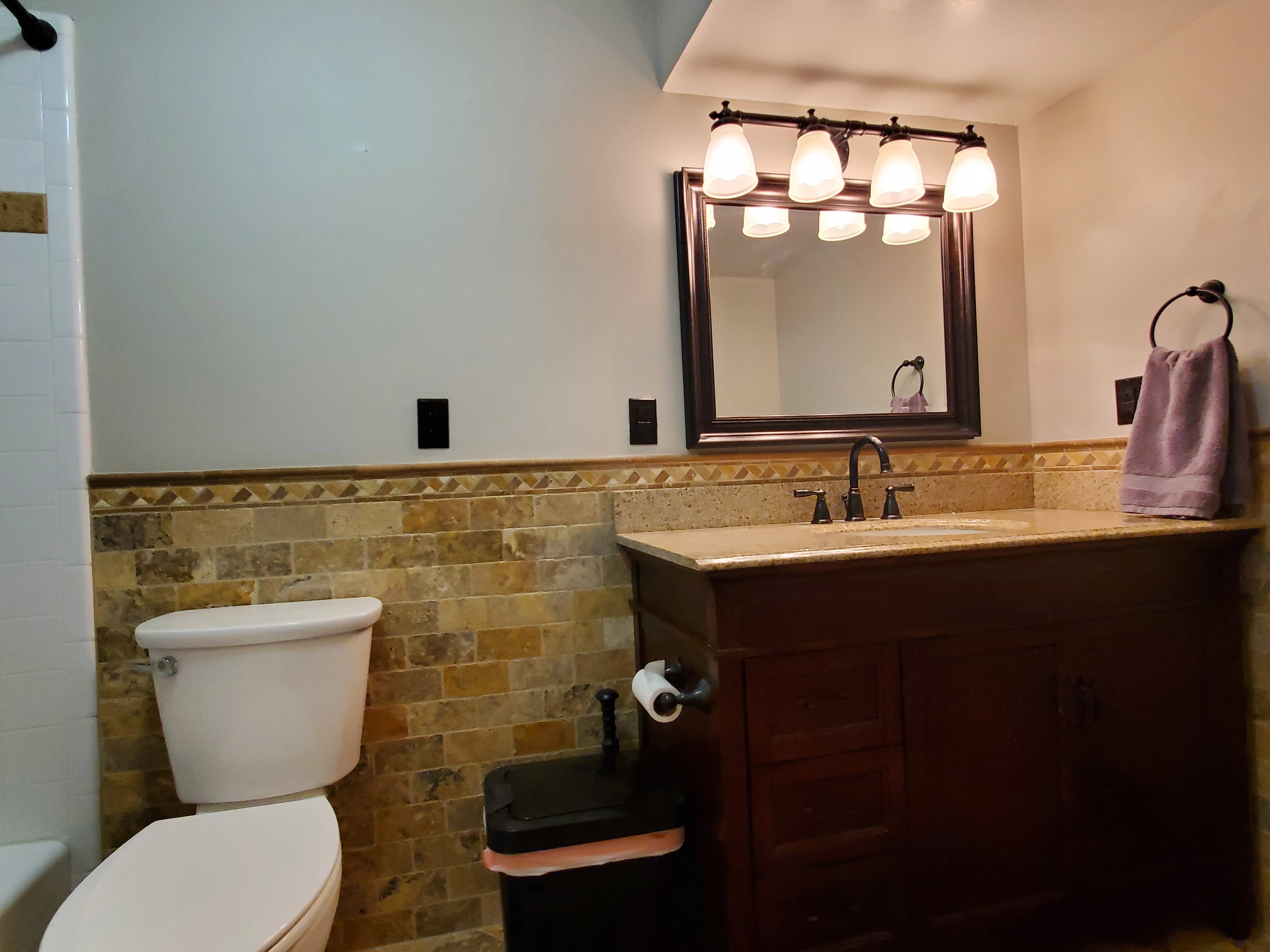 Bathroom featuring a rich wood-tone vanity, a light-toned countertop, and an undermount sink with a dark-finished faucet