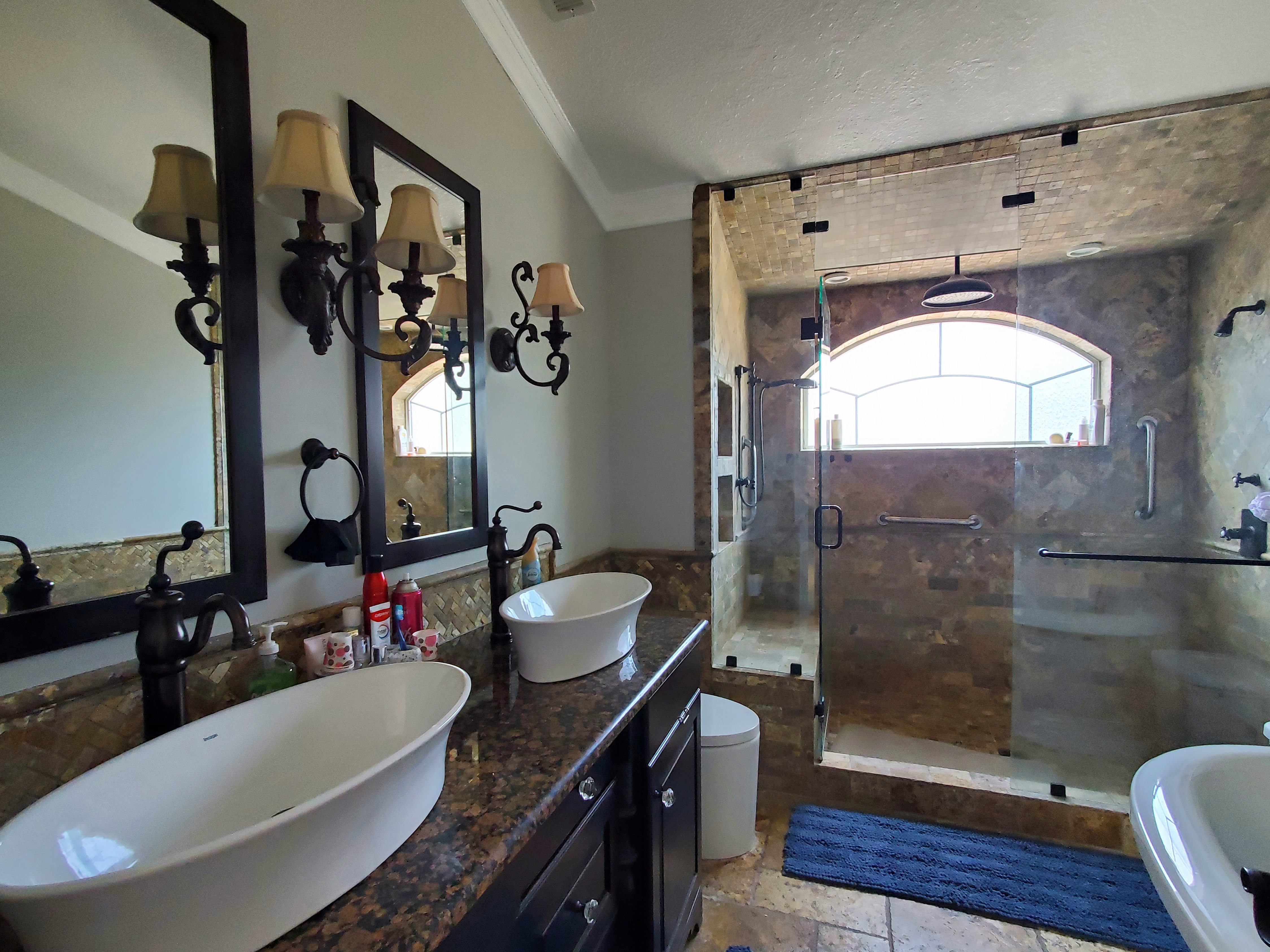 Bathroom featuring a spacious walk-in shower with stone-finish tile, an arched window, and a rain showerhead