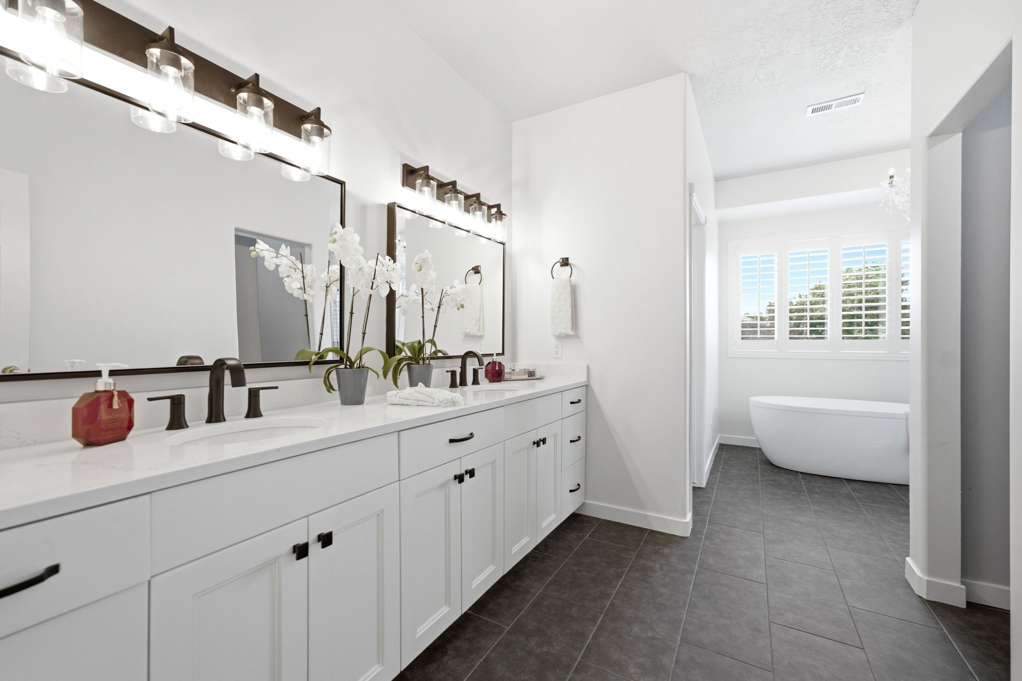 Dual vanity with white cabinetry, quartz countertops, and matte black fixtures