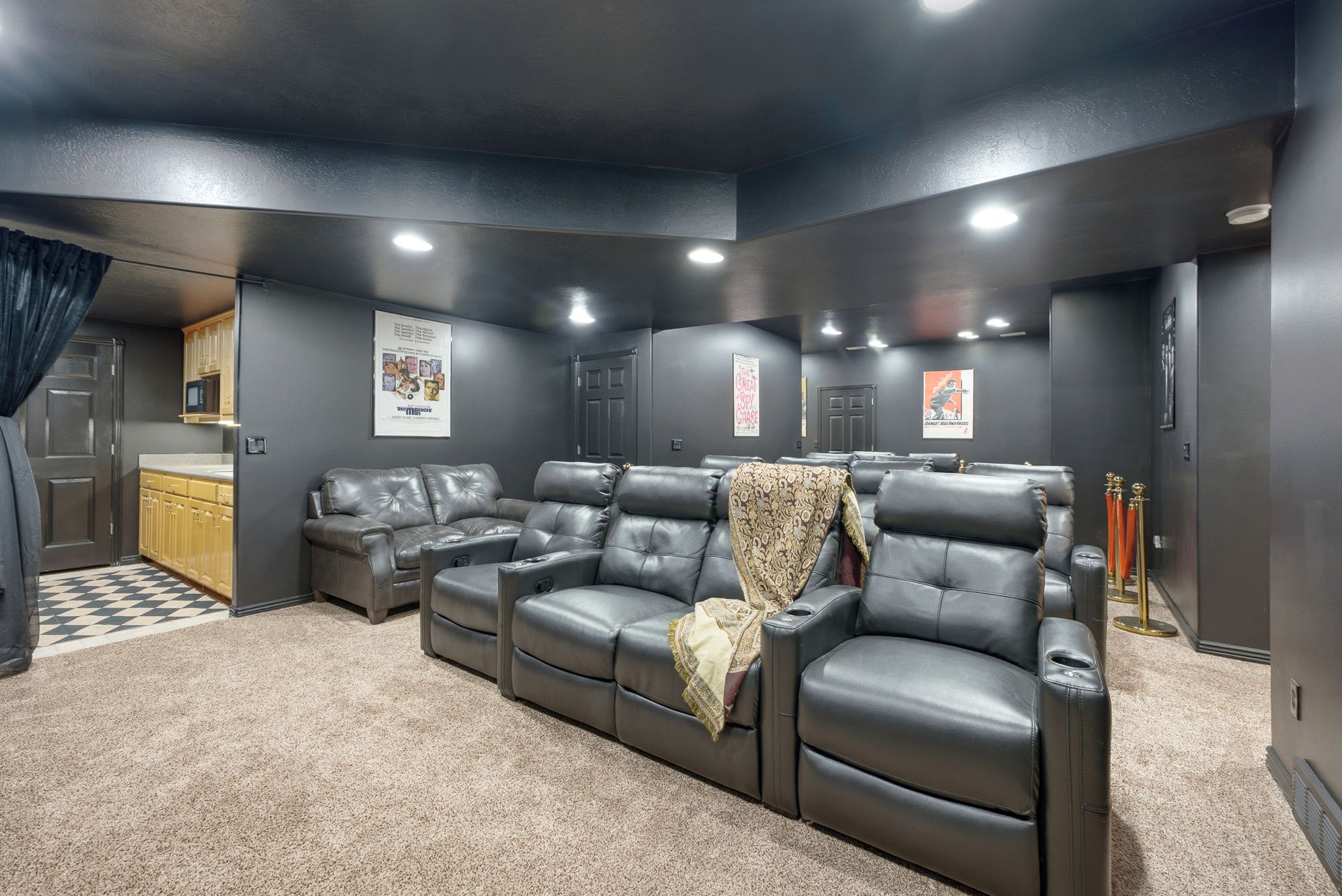 Dedicated entertainment room featuring dark-painted walls and ceiling, recessed lighting, and carpeted flooring