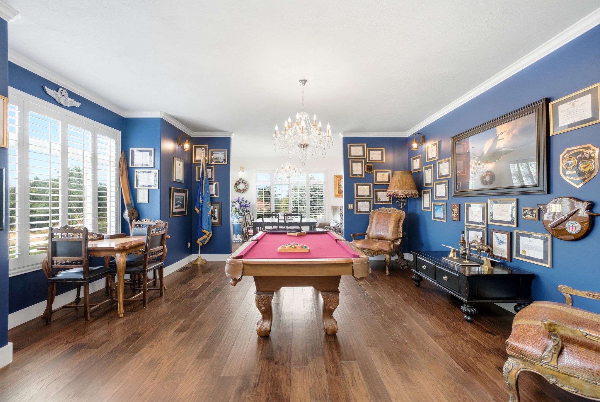 Spacious room featuring rich wood-finish flooring, white crown molding, and plantation shutters