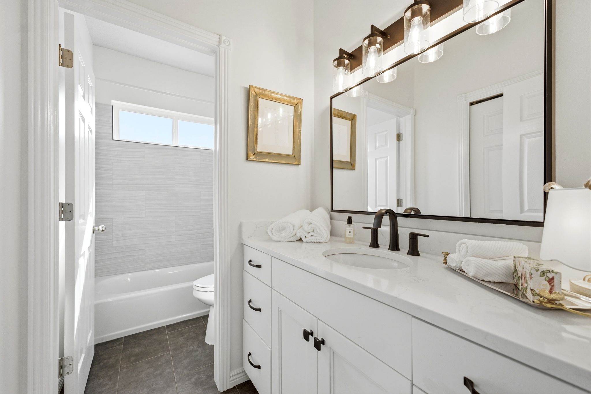 Bathroom featuring a white vanity with integrated sink, dark hardware, and a large wall-mounted mirror