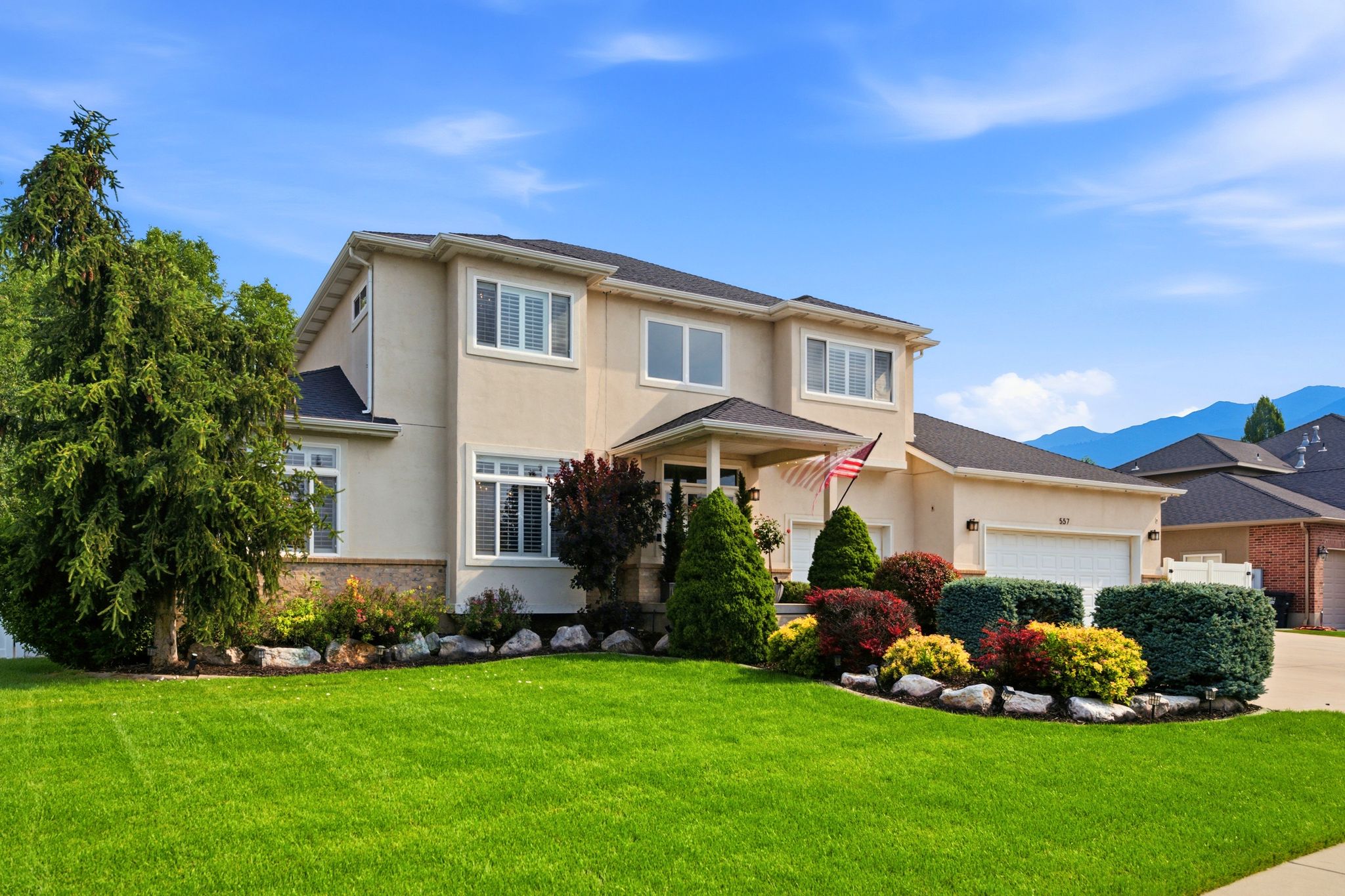 Two-story stucco residence featuring a covered entry, multiple windows with white trim, and an attached two-car garage