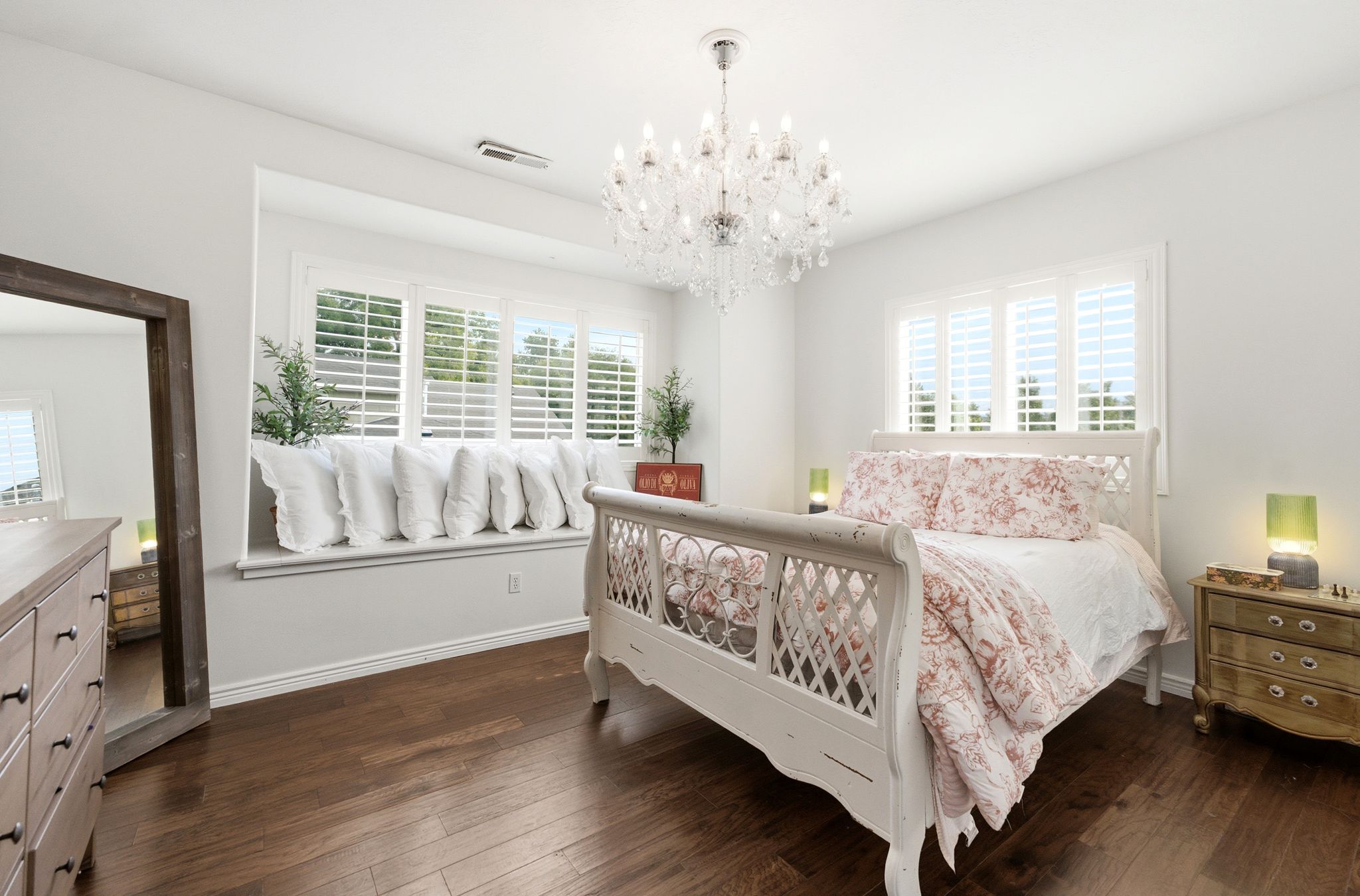 Dark wood-finish flooring complements the bright white walls of this bedroom