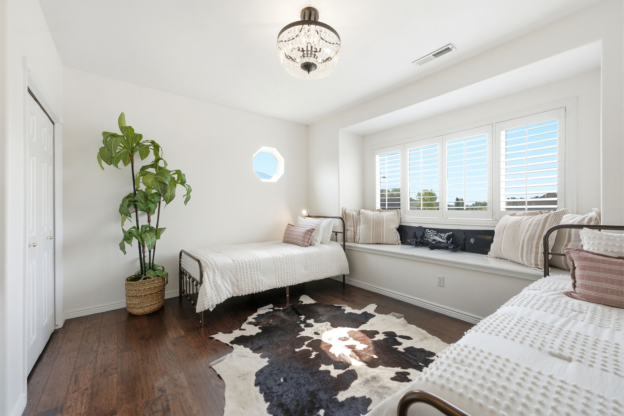 Bright room featuring a wide window seat, plantation shutters, and wood-finish flooring