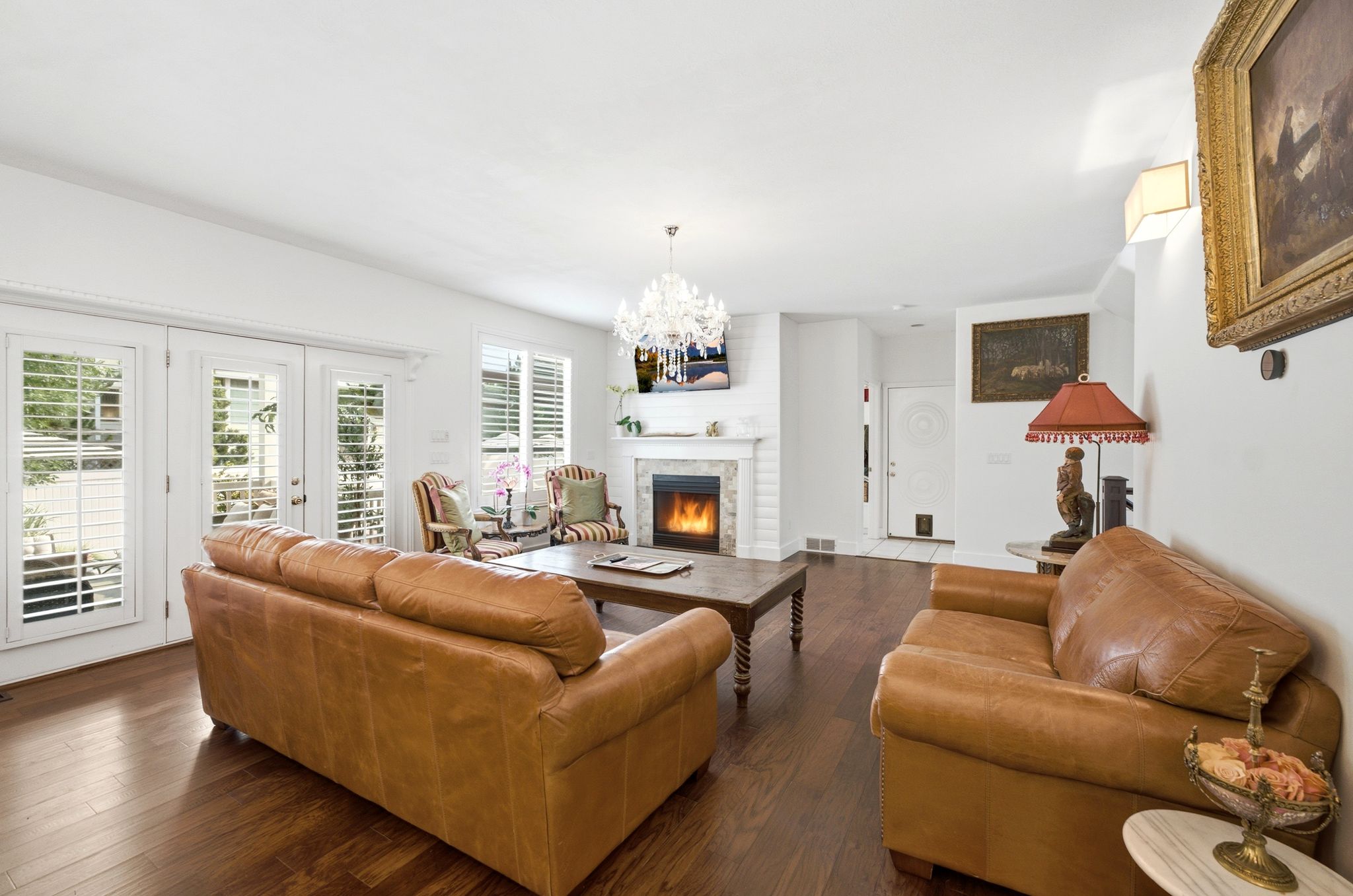 Living room featuring wood-finish flooring, white walls, and a fireplace with a white brick surround and mantel