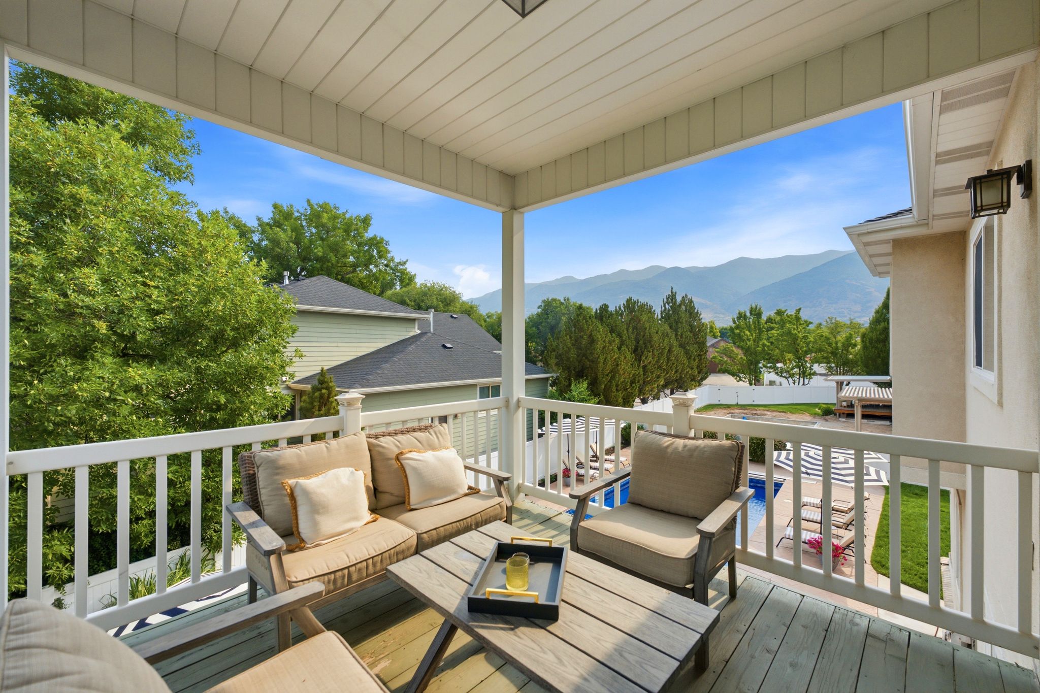 Spacious covered deck featuring wood-finish flooring and white railings