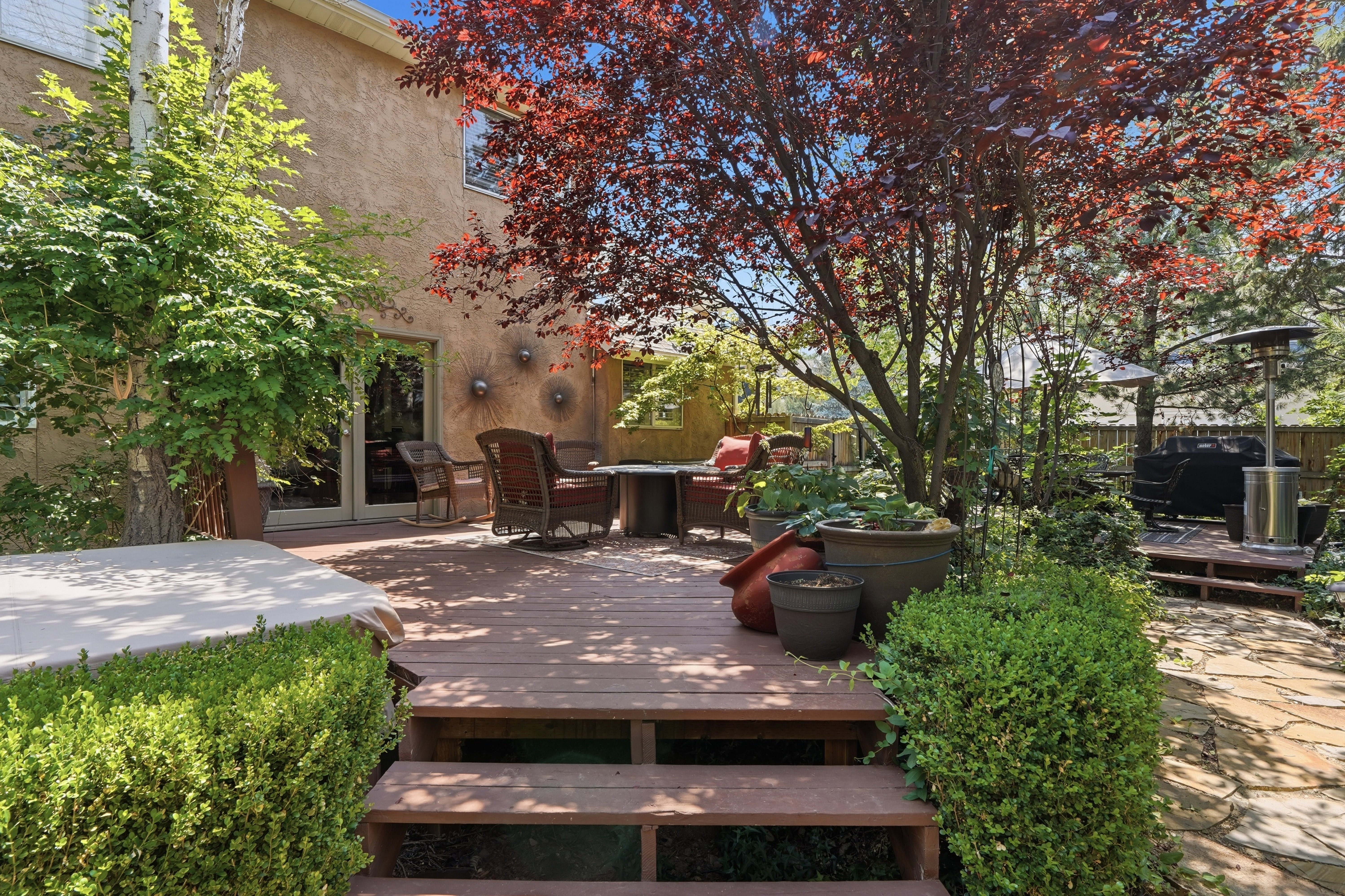 Multi-level wood deck featuring mature landscaping, and stone paver patio elements