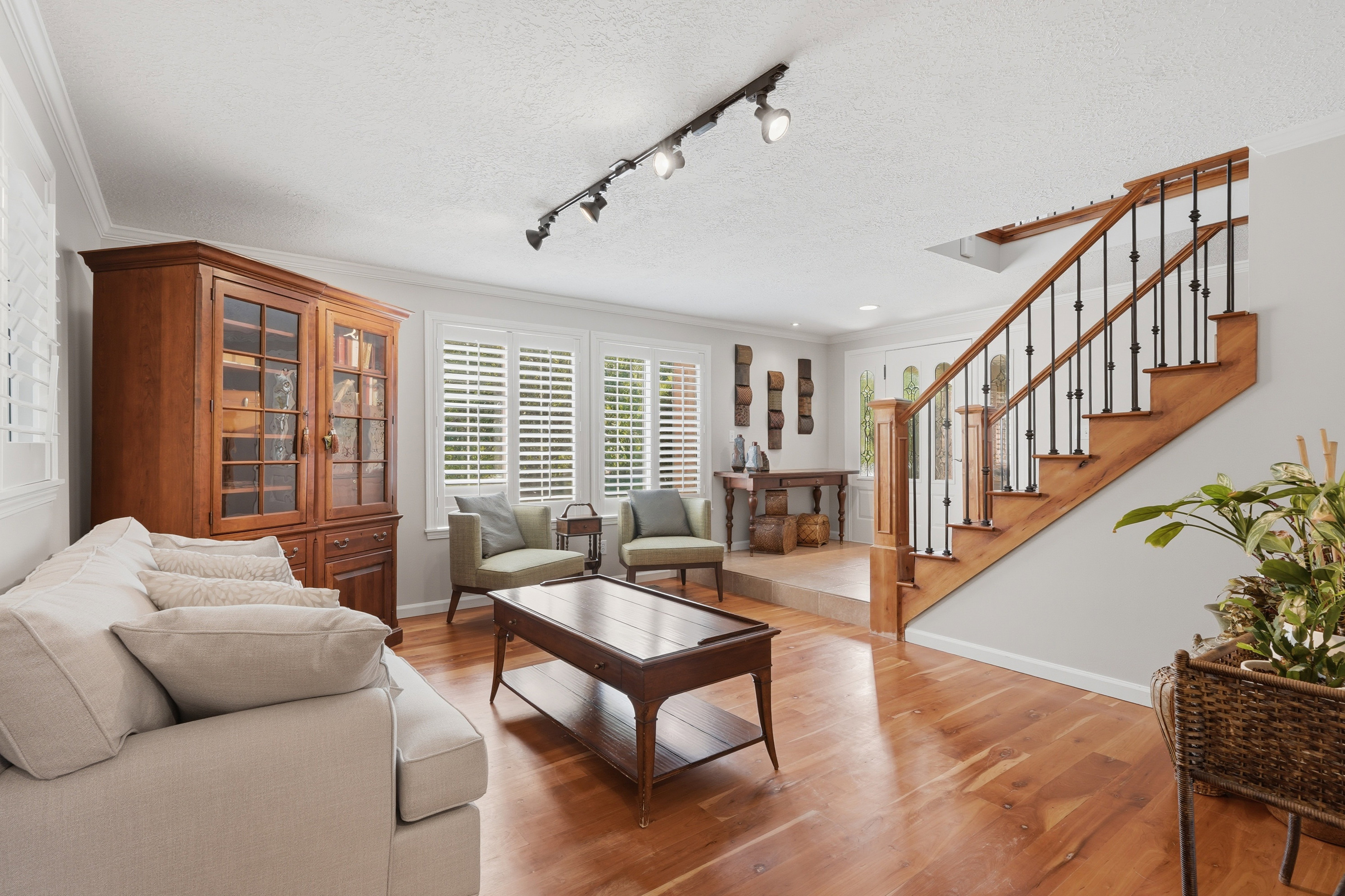 Living area featuring wood flooring, white plantation shutters