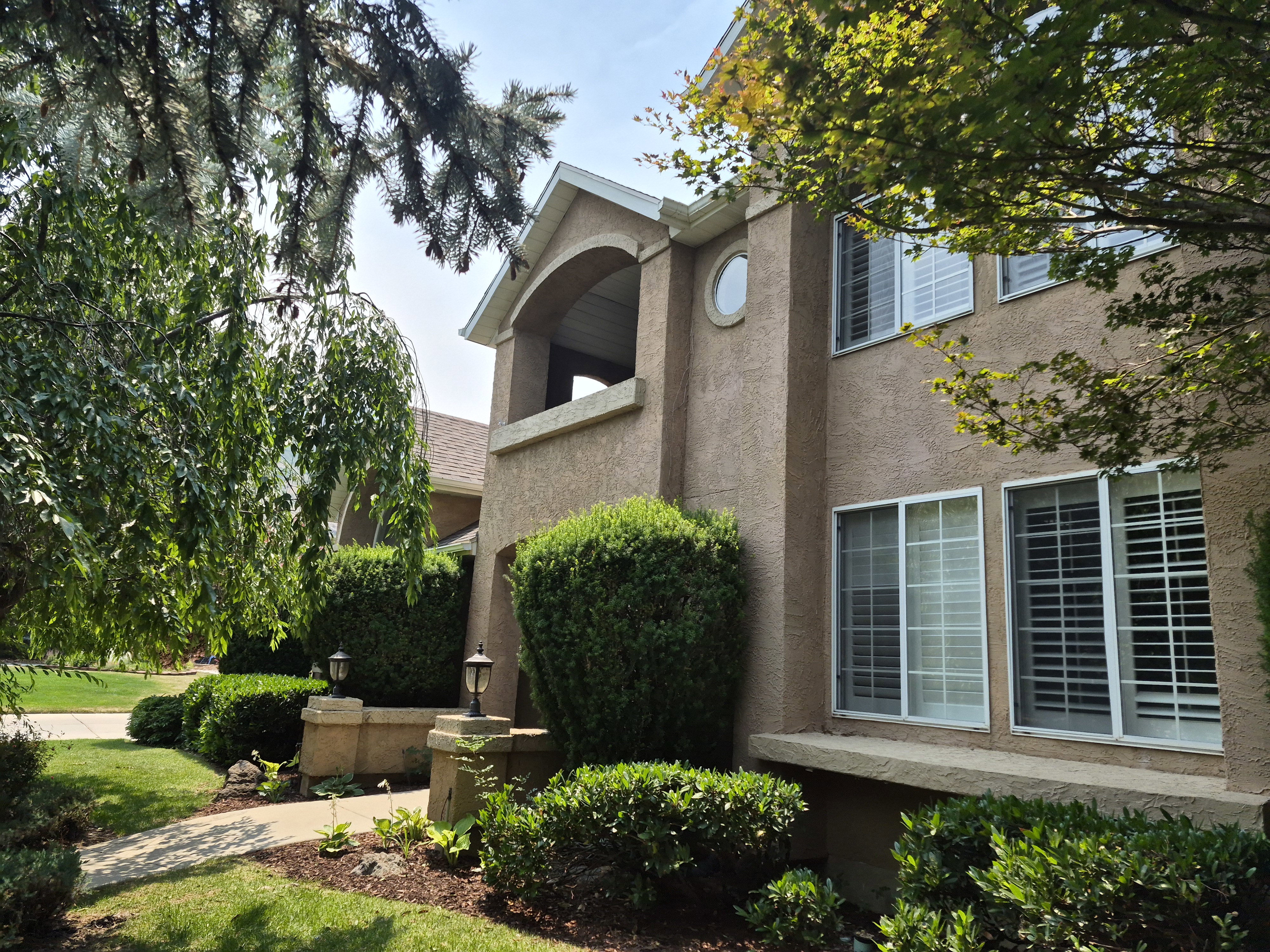 Stucco exterior featuring an arched balcony and a circular accent window