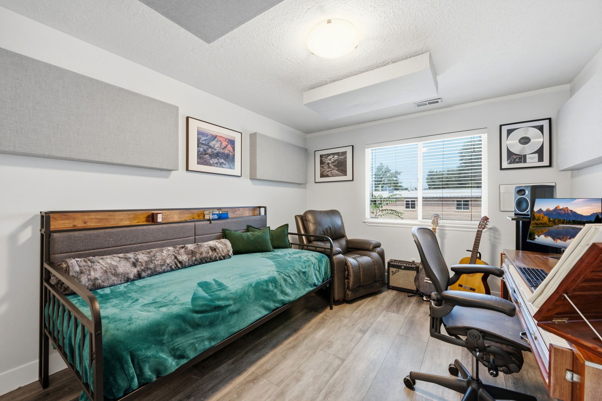 Versatile room featuring wood-finish flooring, a large window with horizontal blinds, built-in sound panels, and a flush-mount ceiling light fixture
