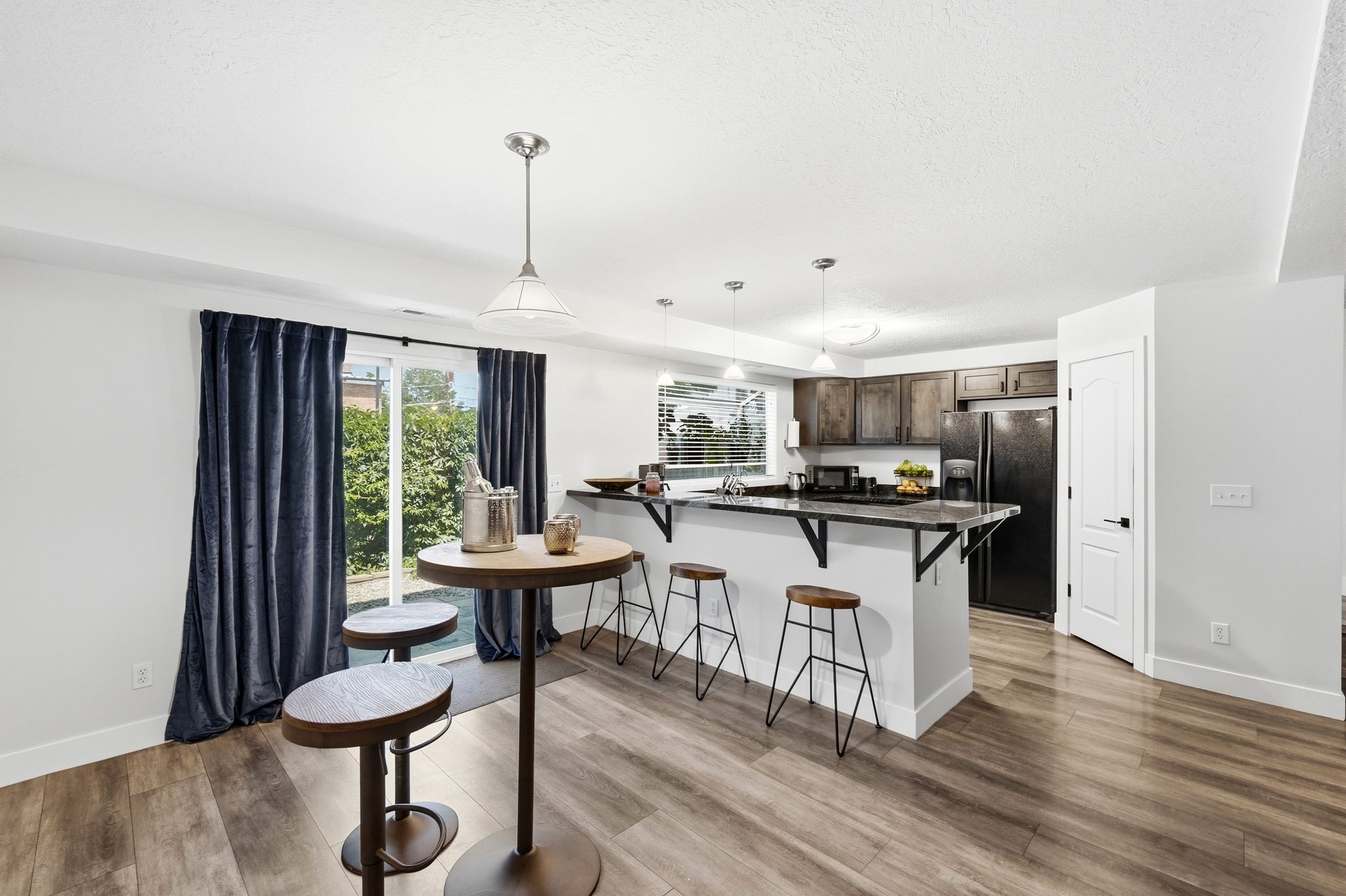 Kitchen with wood-finish flooring, dark cabinetry, and black appliances
