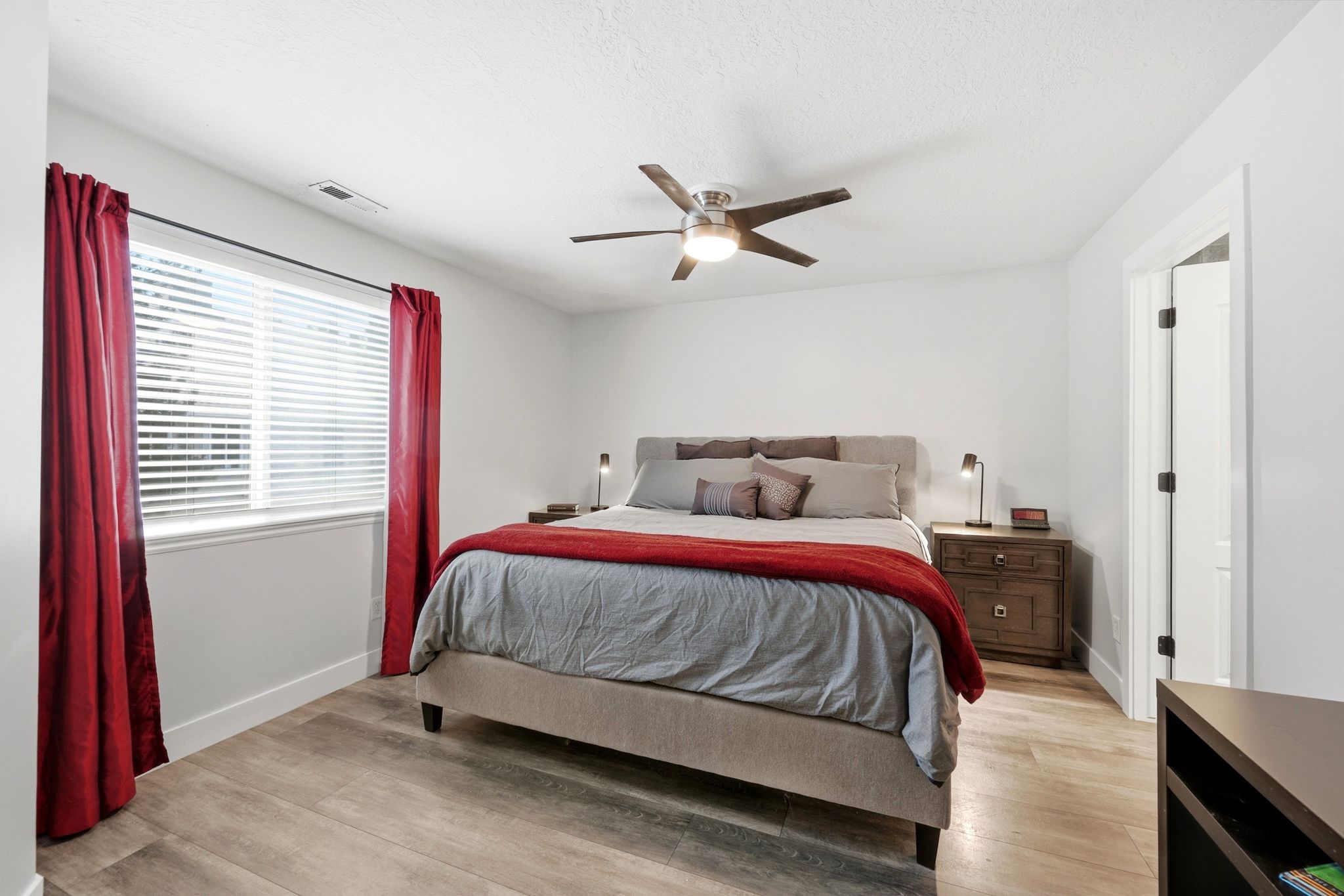 Bedroom featuring wood-finish flooring, a ceiling fan with integrated lighting, a window with blinds, and white trim