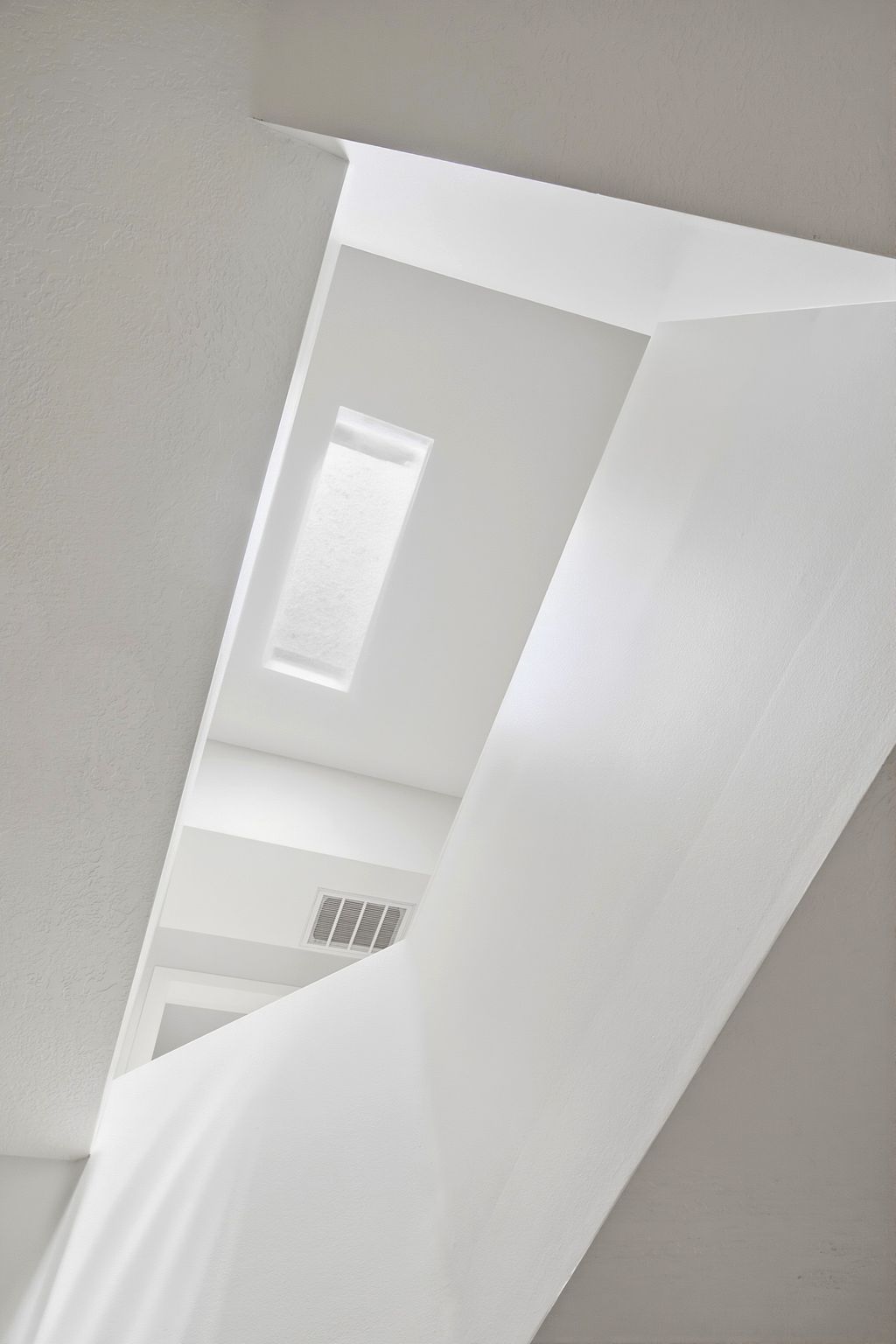 Architectural ceiling details with a skylight, white walls, and a visible air vent