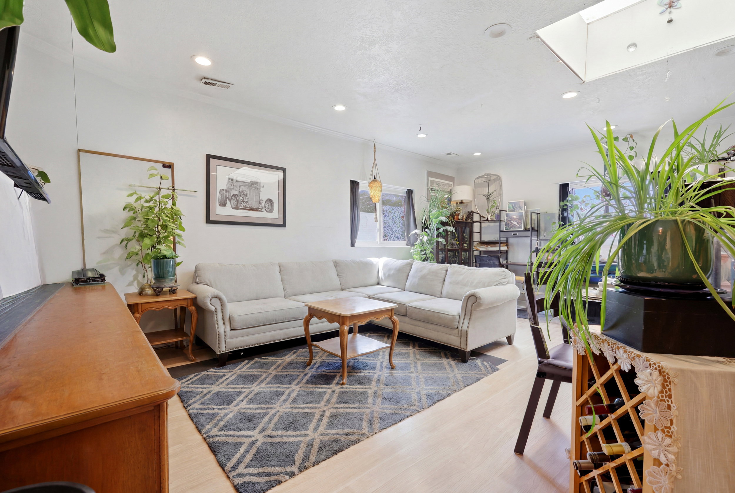 Living area with light-toned wood-finish flooring, recessed lighting, and a skylight