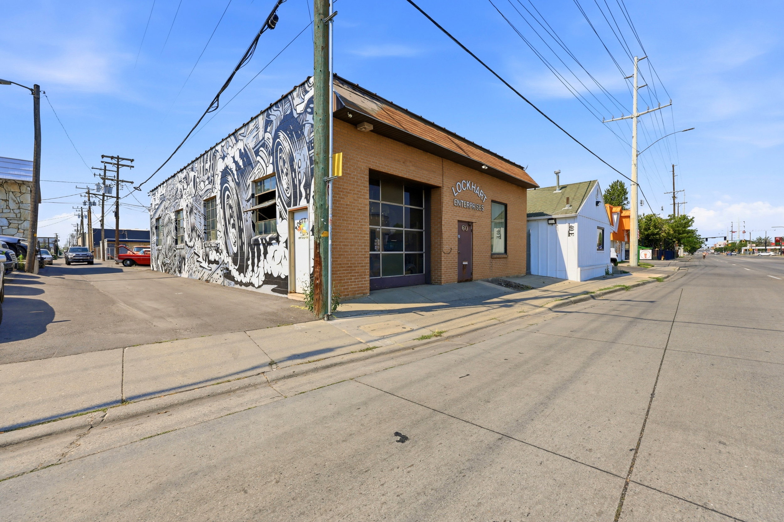 Brick commercial building featuring a large glass garage door, brown entry door, and a street-facing mural