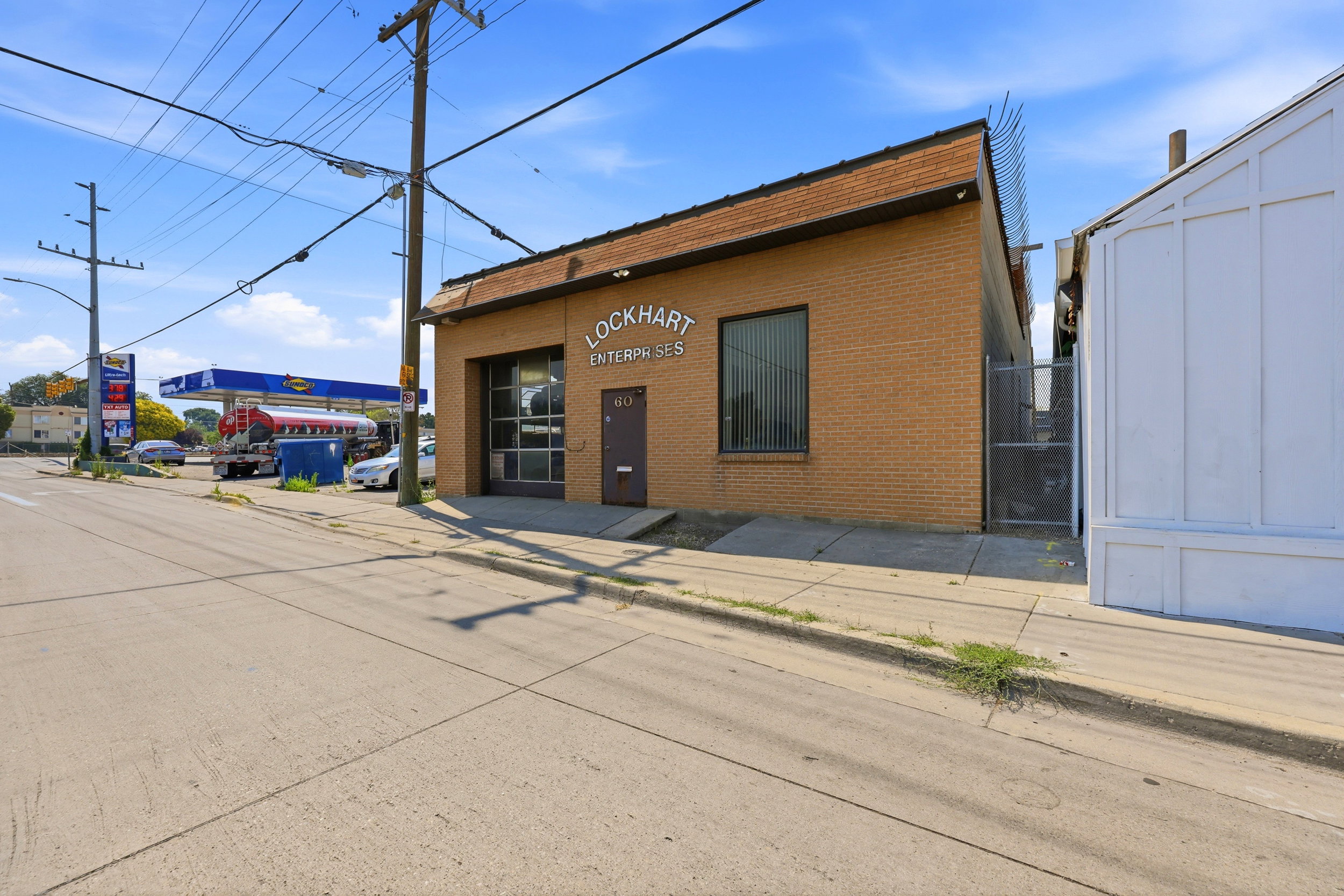 Brick commercial building featuring a large roll-up door, prominent signage, and a pedestrian entrance