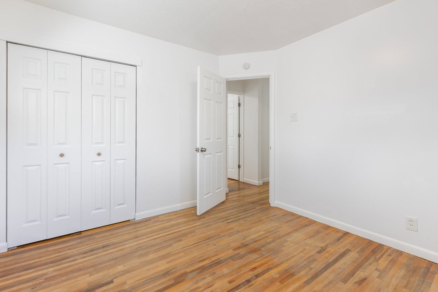 Room featuring wood-finish flooring, white walls, and bright white trim