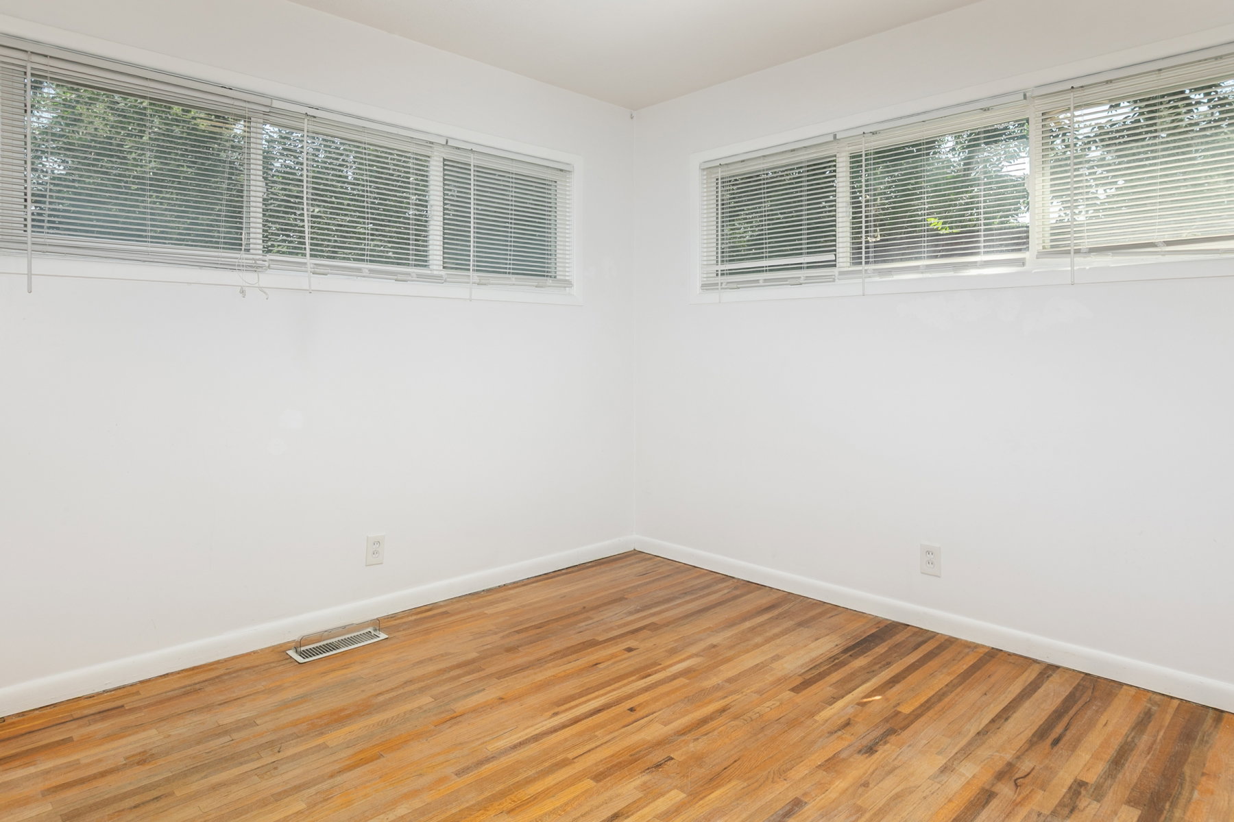 Light-filled room featuring wood-finish flooring, white baseboards, and bright white walls