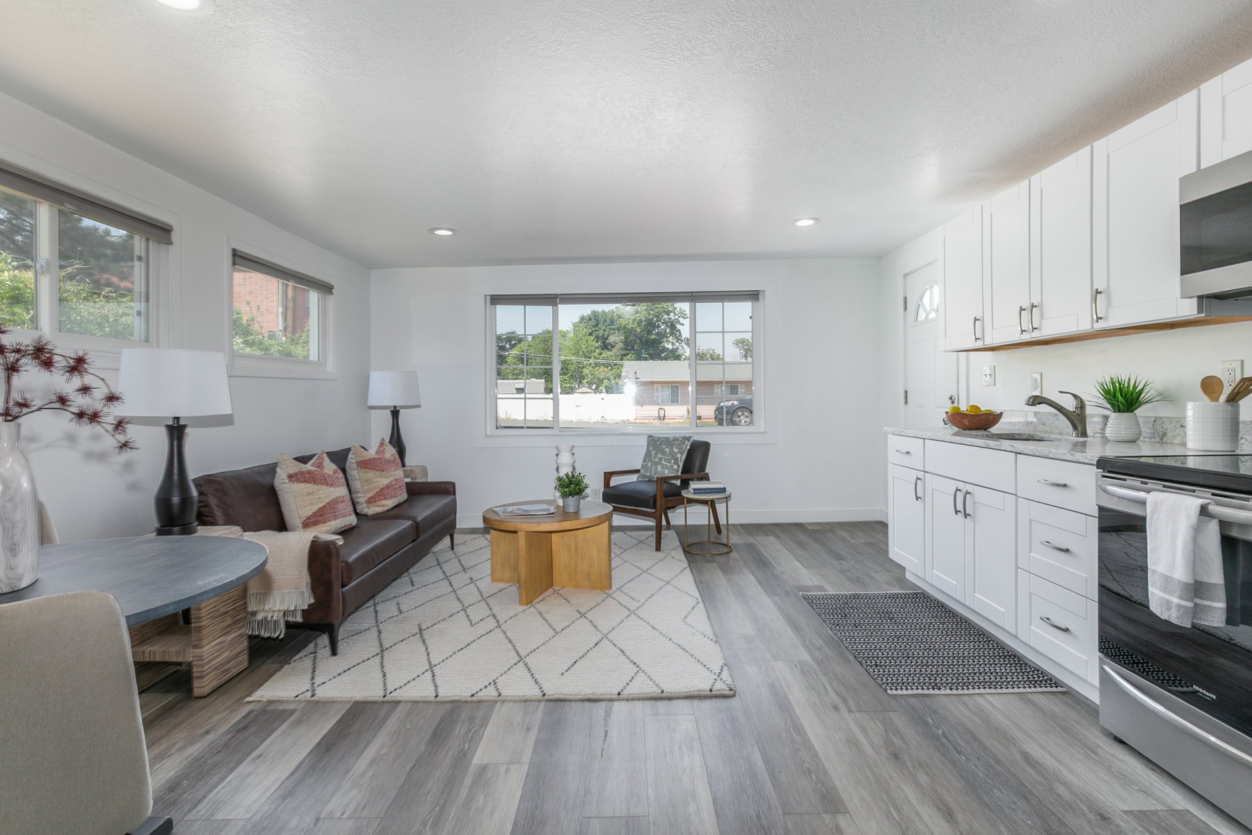 Open-concept living space featuring wood-finish flooring throughout, recessed lighting, and white walls