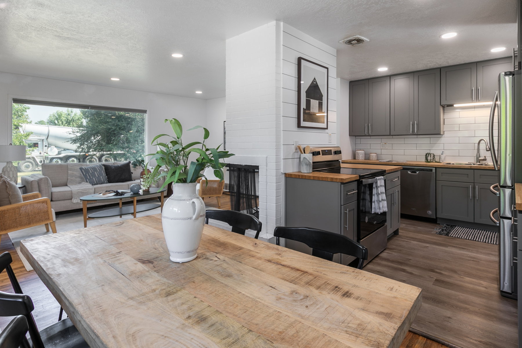 Open-concept living space featuring a kitchen with gray cabinetry, wood-finish countertops, and stainless steel appliances