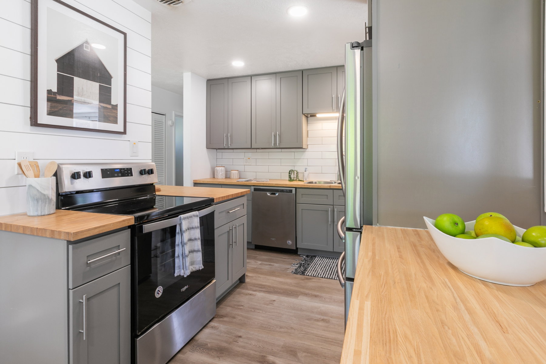Kitchen featuring wood-finish countertops, stainless steel appliances, gray cabinetry, subway tile backsplash, and wood-finish flooring