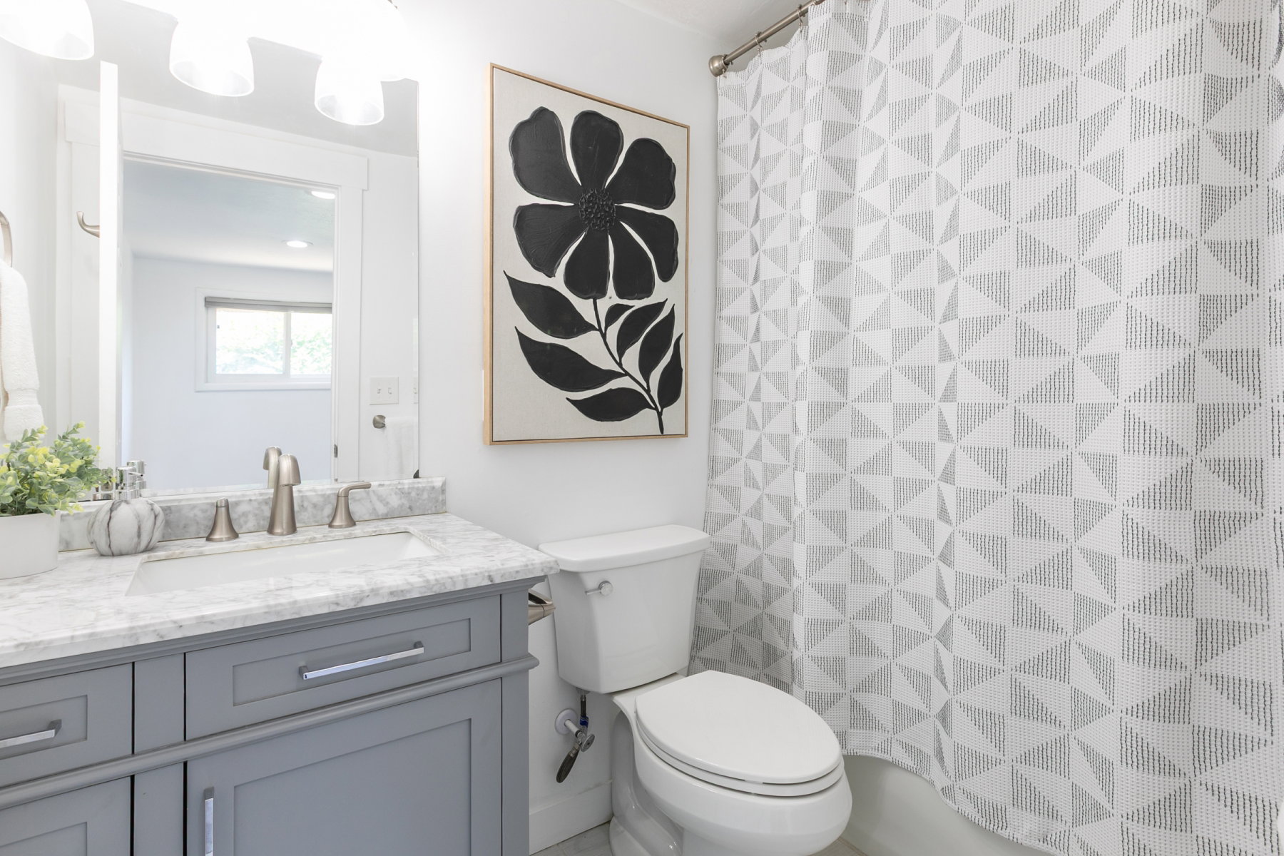Bathroom featuring a gray vanity with a stone countertop, an undermount sink, and brushed nickel fixtures