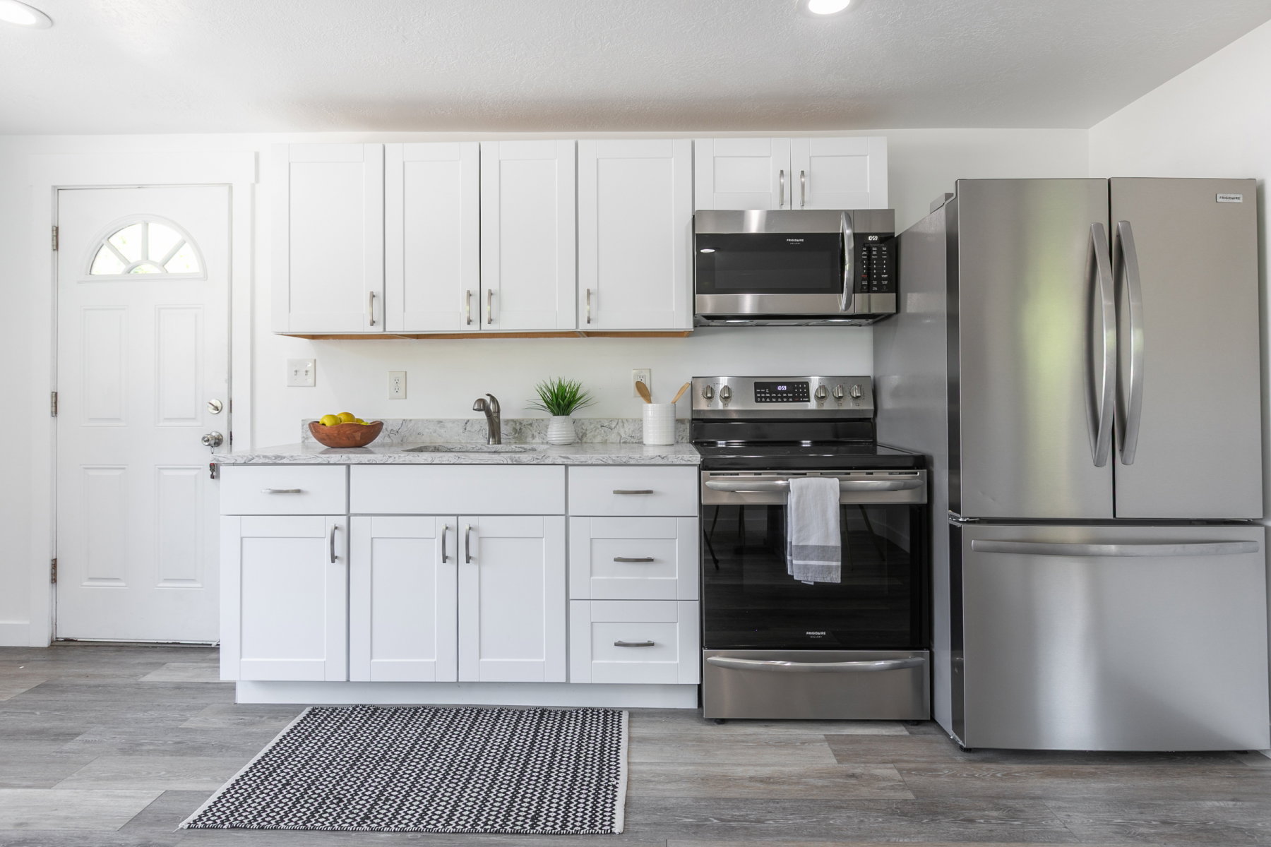 Modern kitchen featuring white shaker cabinetry, stainless steel appliances, a stainless steel sink, and wood-finish flooring