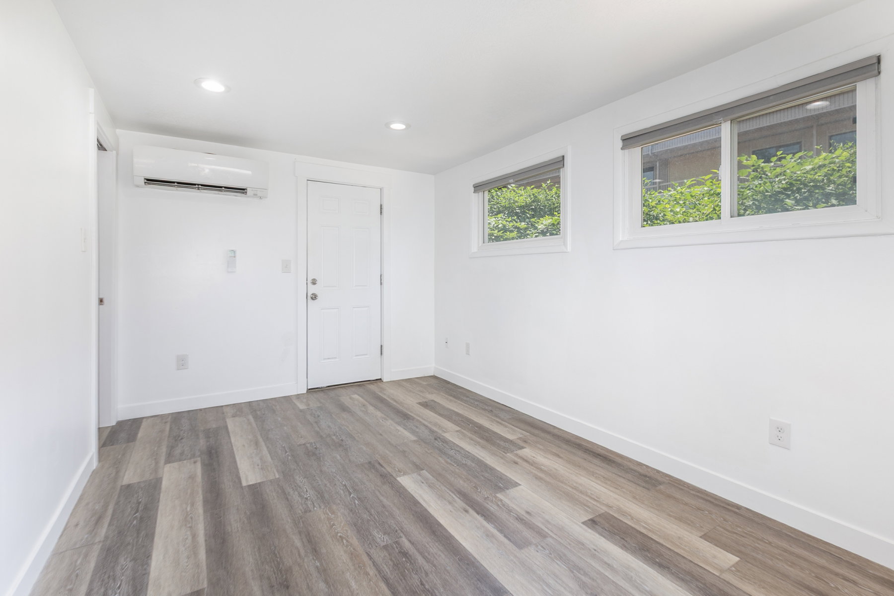 Bright room featuring wood-finish flooring, white walls, and recessed lighting
